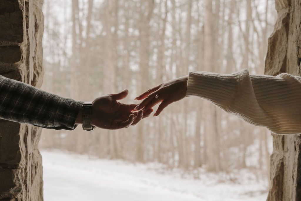 Hands reaching across a snowy winter landscape creating a connection.