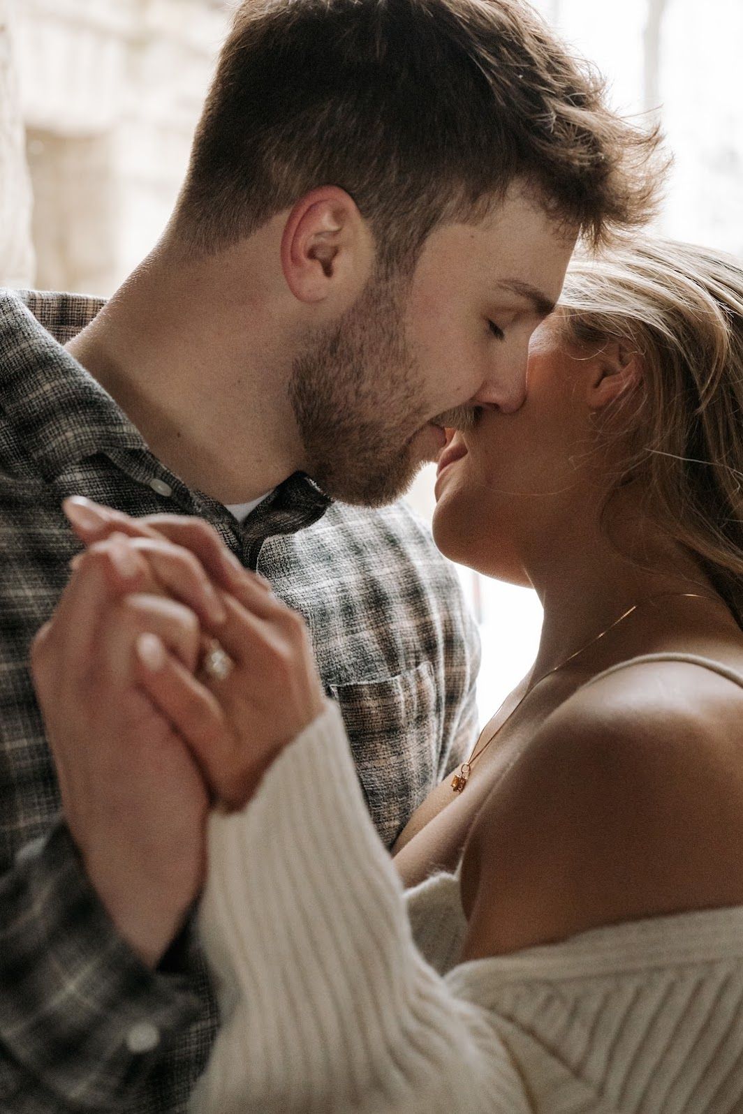 Romantic couple sharing tender moment in soft window light.