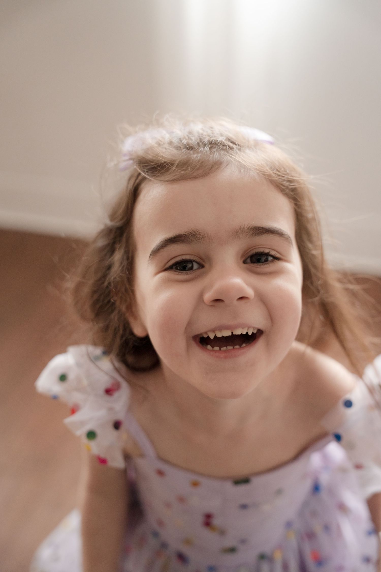 Close-up of child laughing joyfully while wearing polka dot dress.