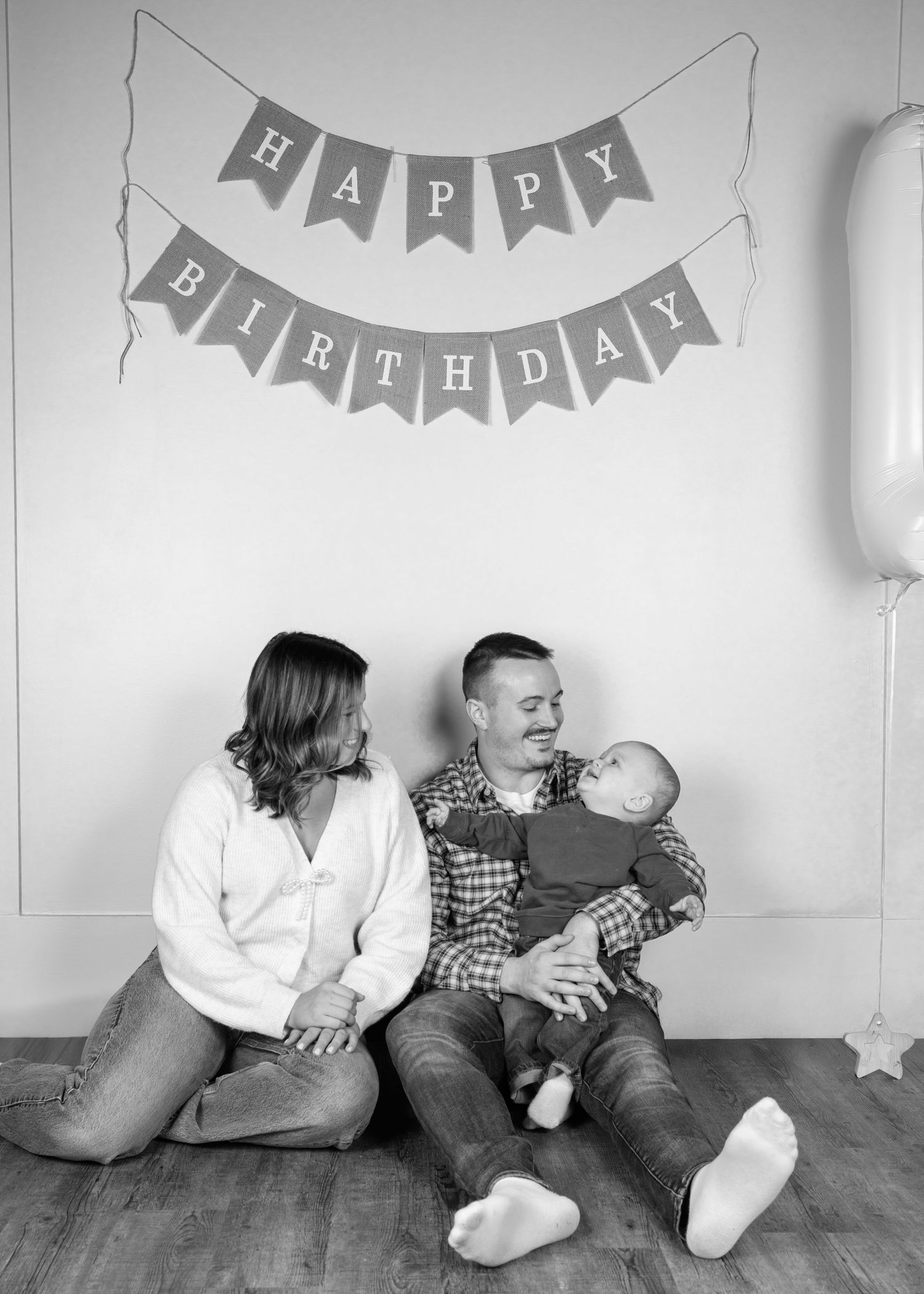Family studio photoshoot with happy birthday banner in black and white.