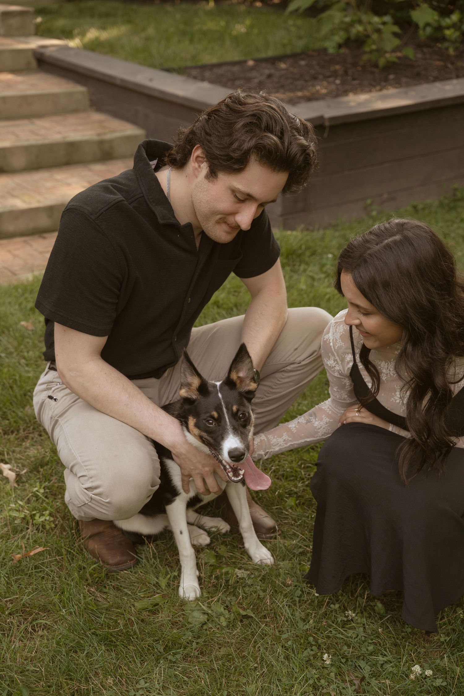 Couple sits on grass with their dog during outdoor couples photo session.
