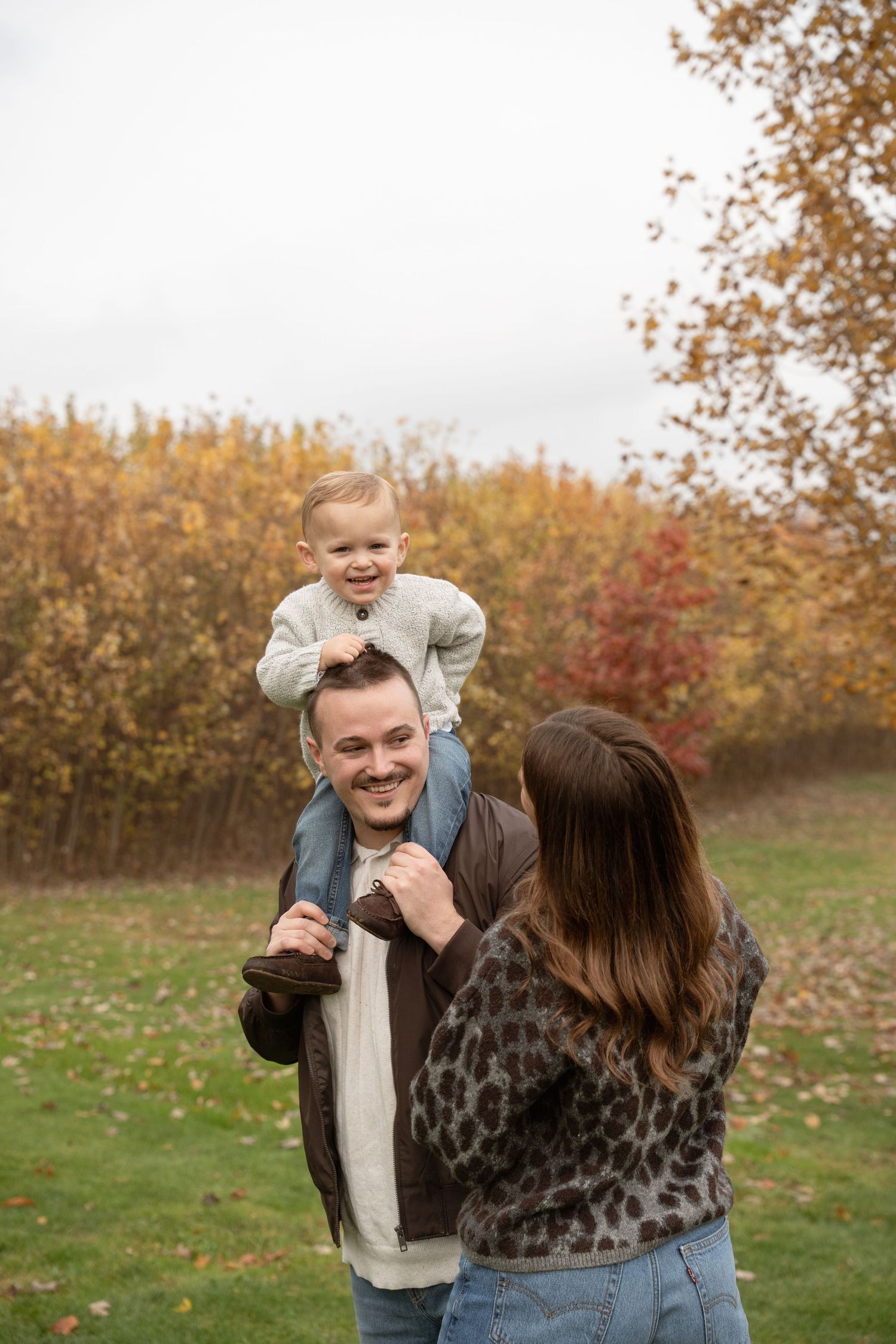 Playful autumn family photo session with fall foliage in background.