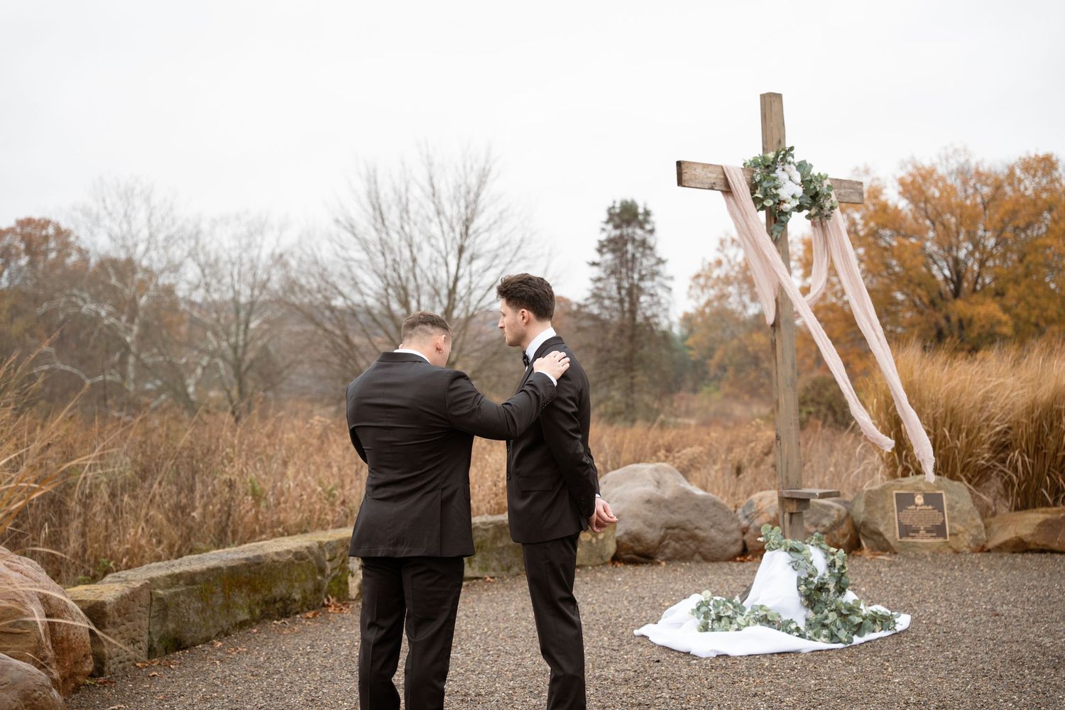 Bsst man praying over groom on an autumn day before the ceremony.