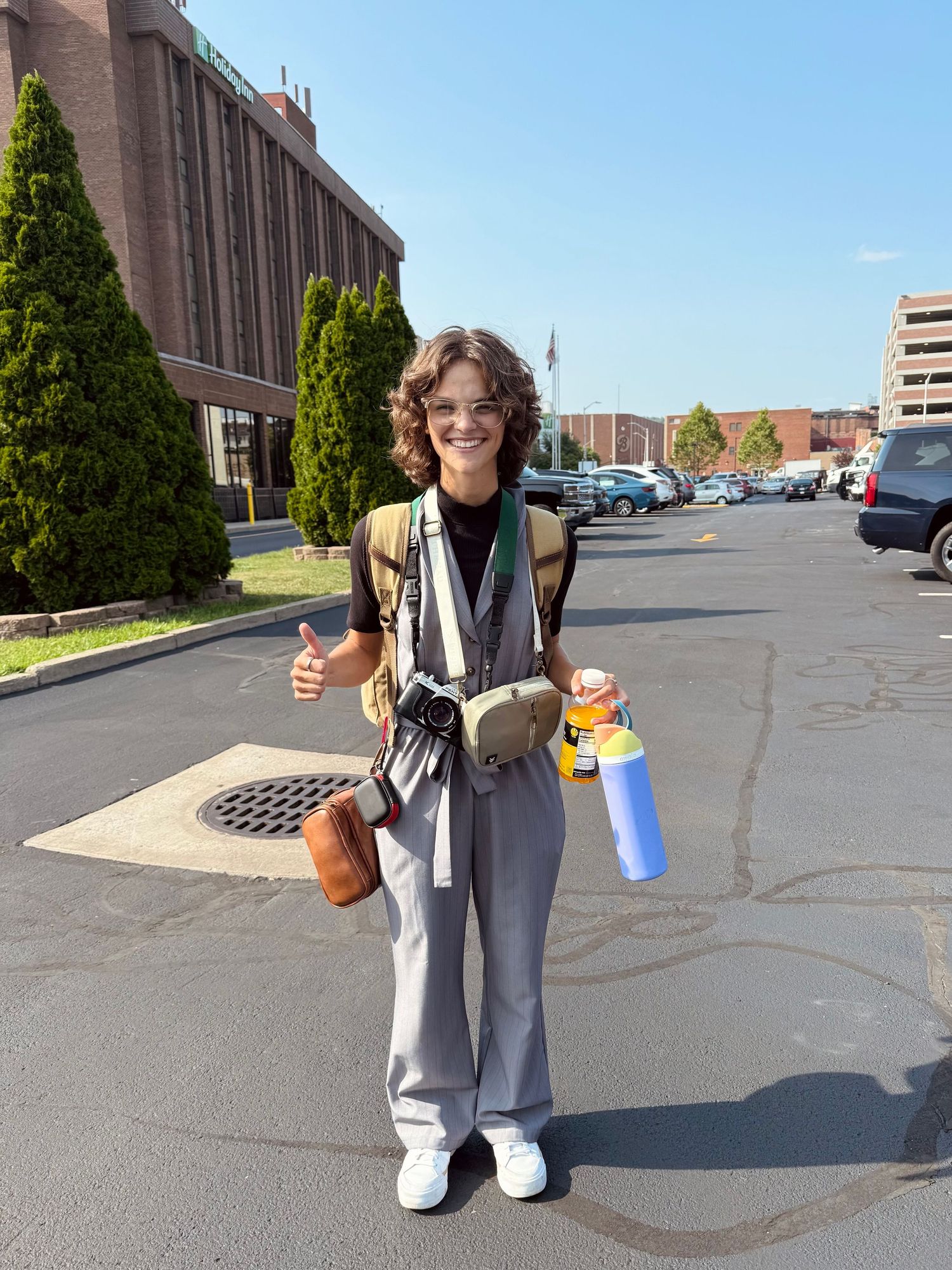 Alexa playfully packed up during a wedding day in sunny hotel parking lot.