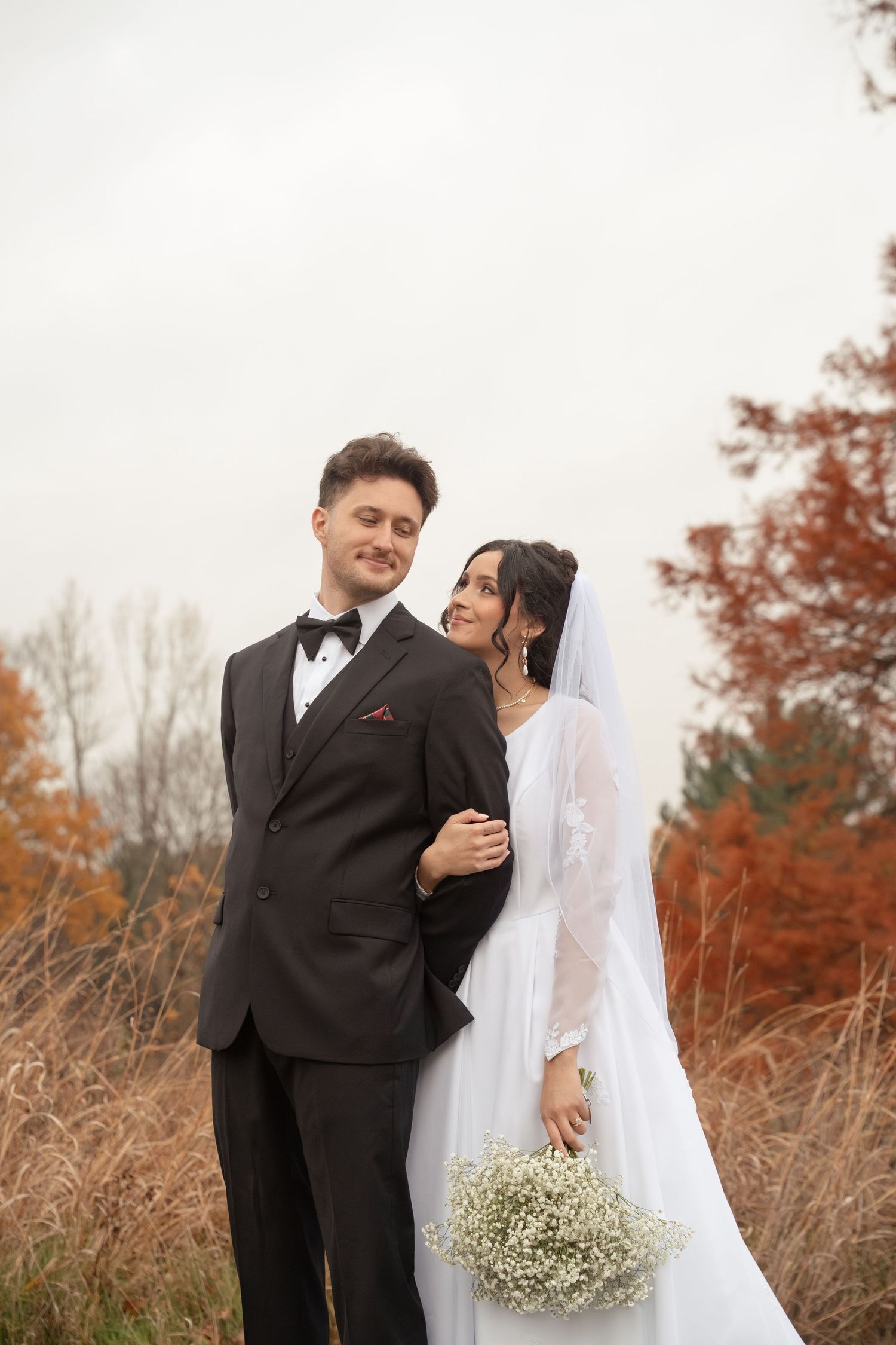 A couple shares a tender moment during their fall wedding with baby's breath bouquet.