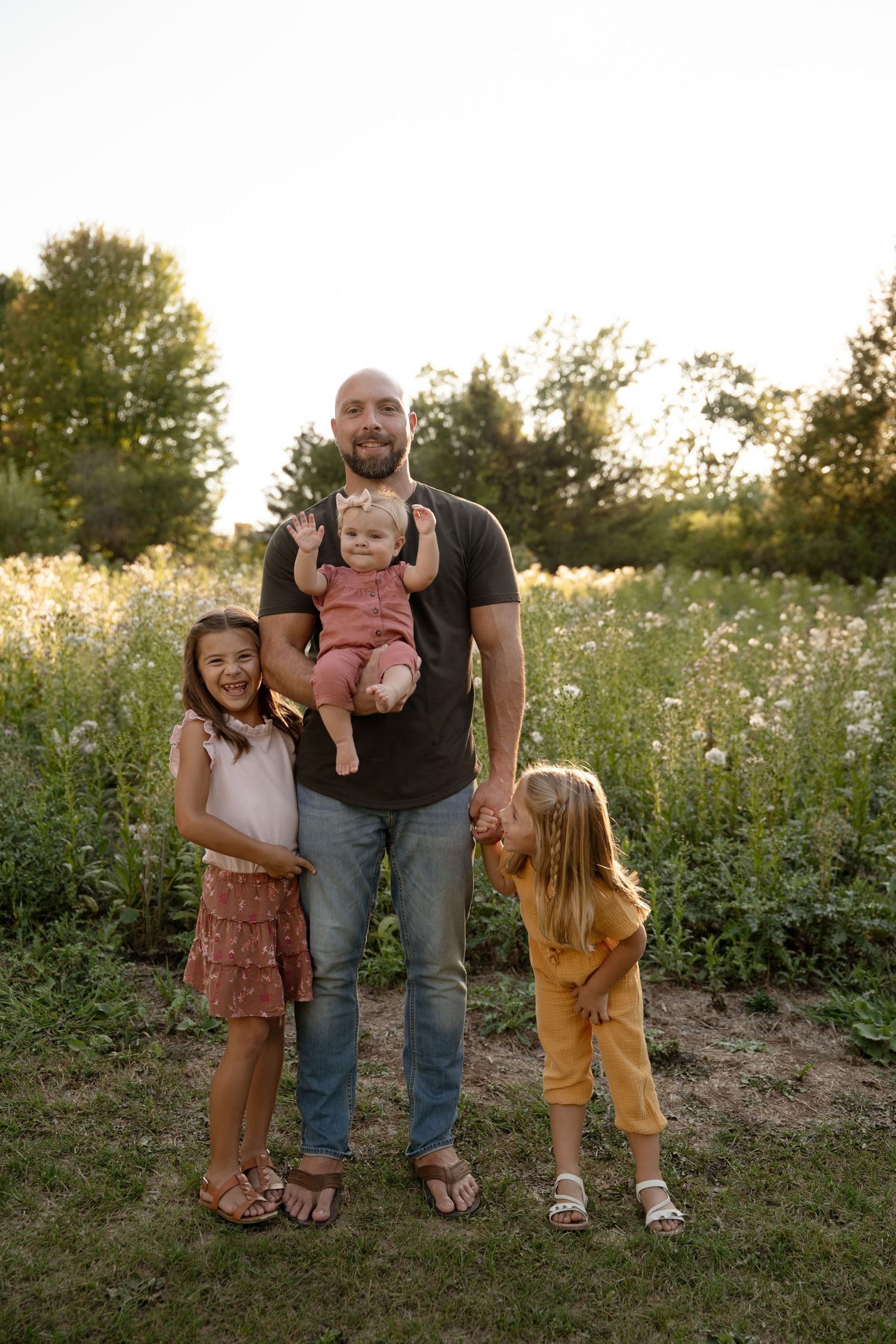 Family standing together in a wildflower field at sunset.