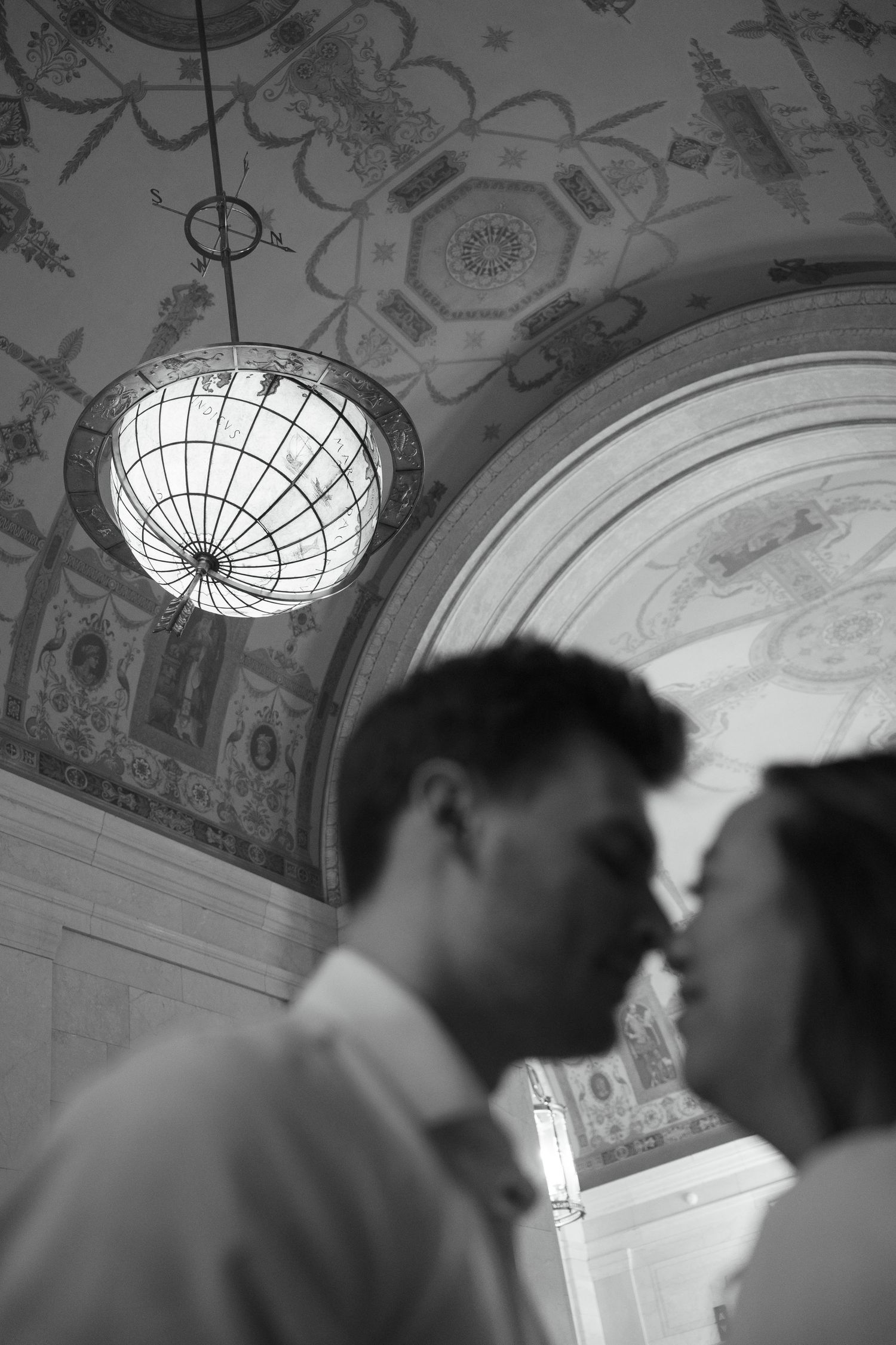 Ornate ceiling with decorative light fixtures in a grand interior space highlighting the couple silhouette.