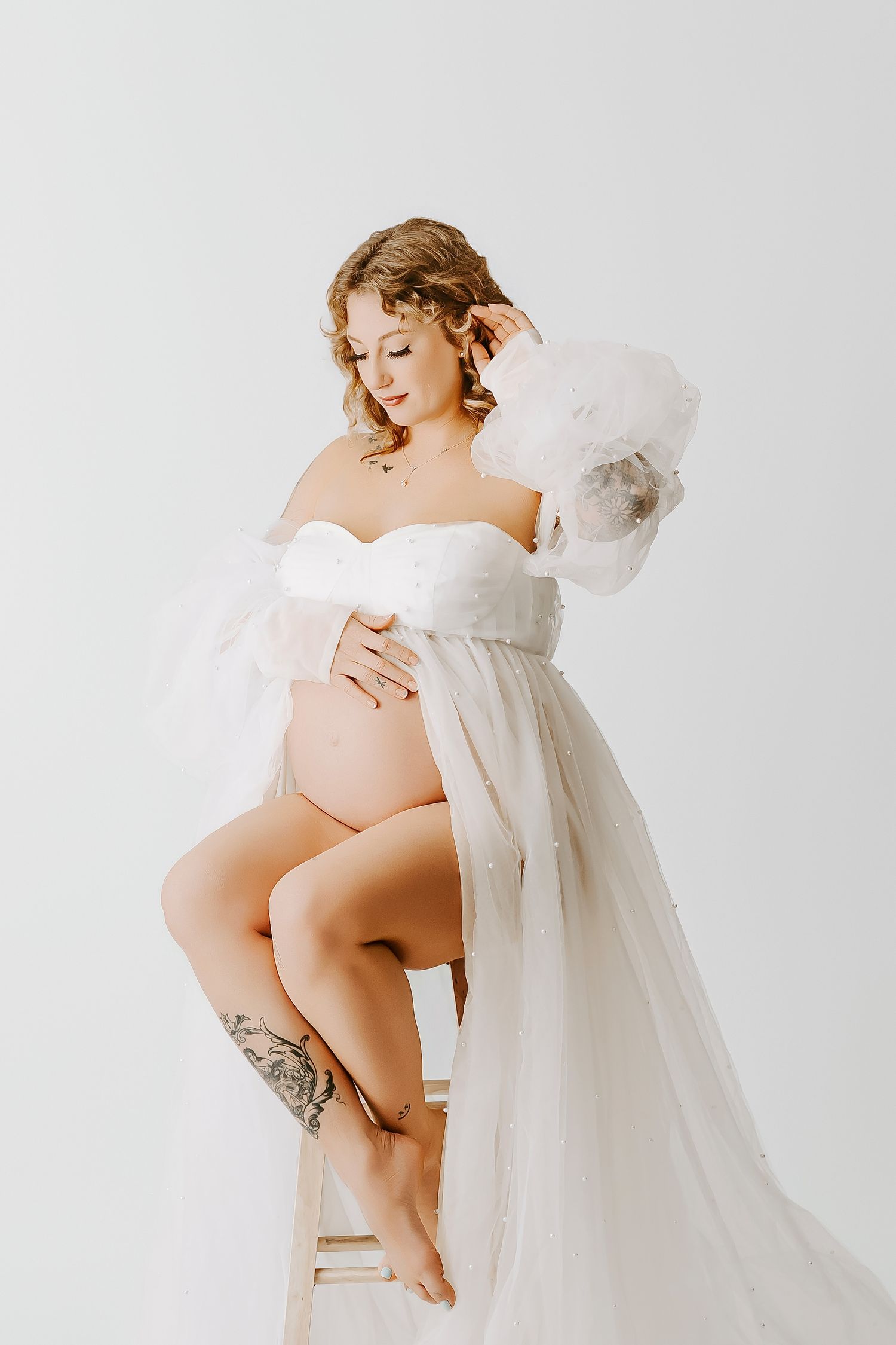 Artistic maternity photo series showing a pregnant woman in white fabric against light background.