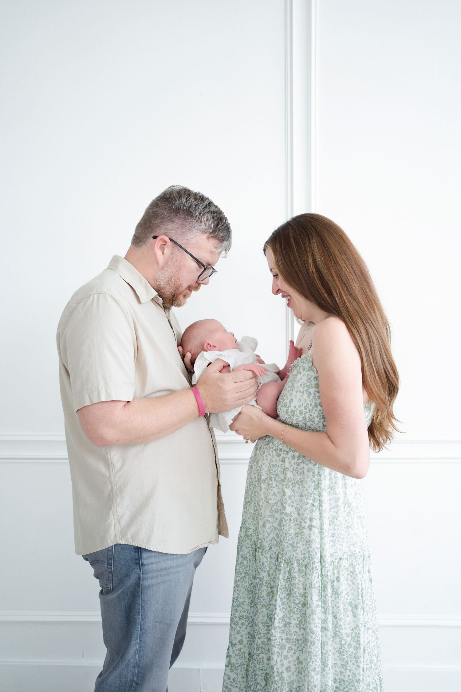 A series of intimate moments between parents and their newborn baby in a bright white room.