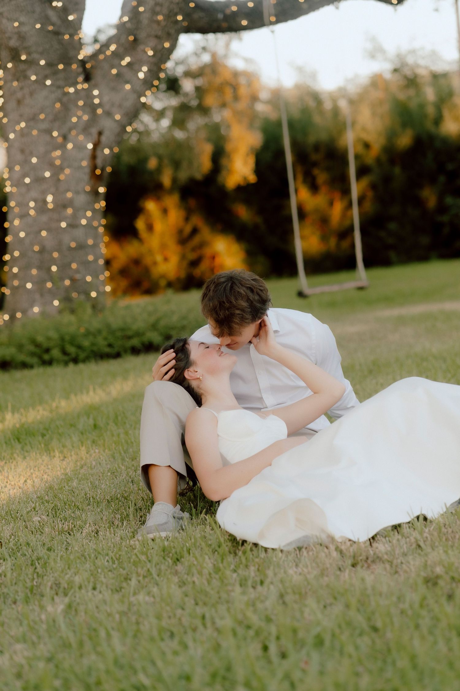 A dreamy outdoor photo session with fairy lights twinkling in the background and soft grass below.