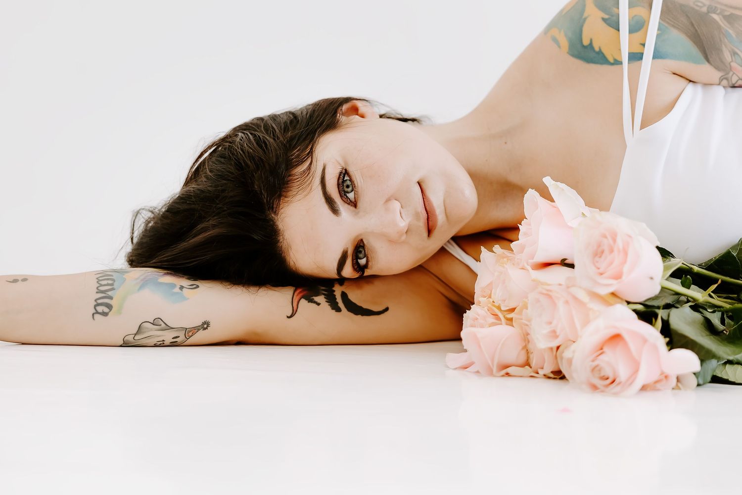 Artistic boudoir series with pink roses and white backdrop.