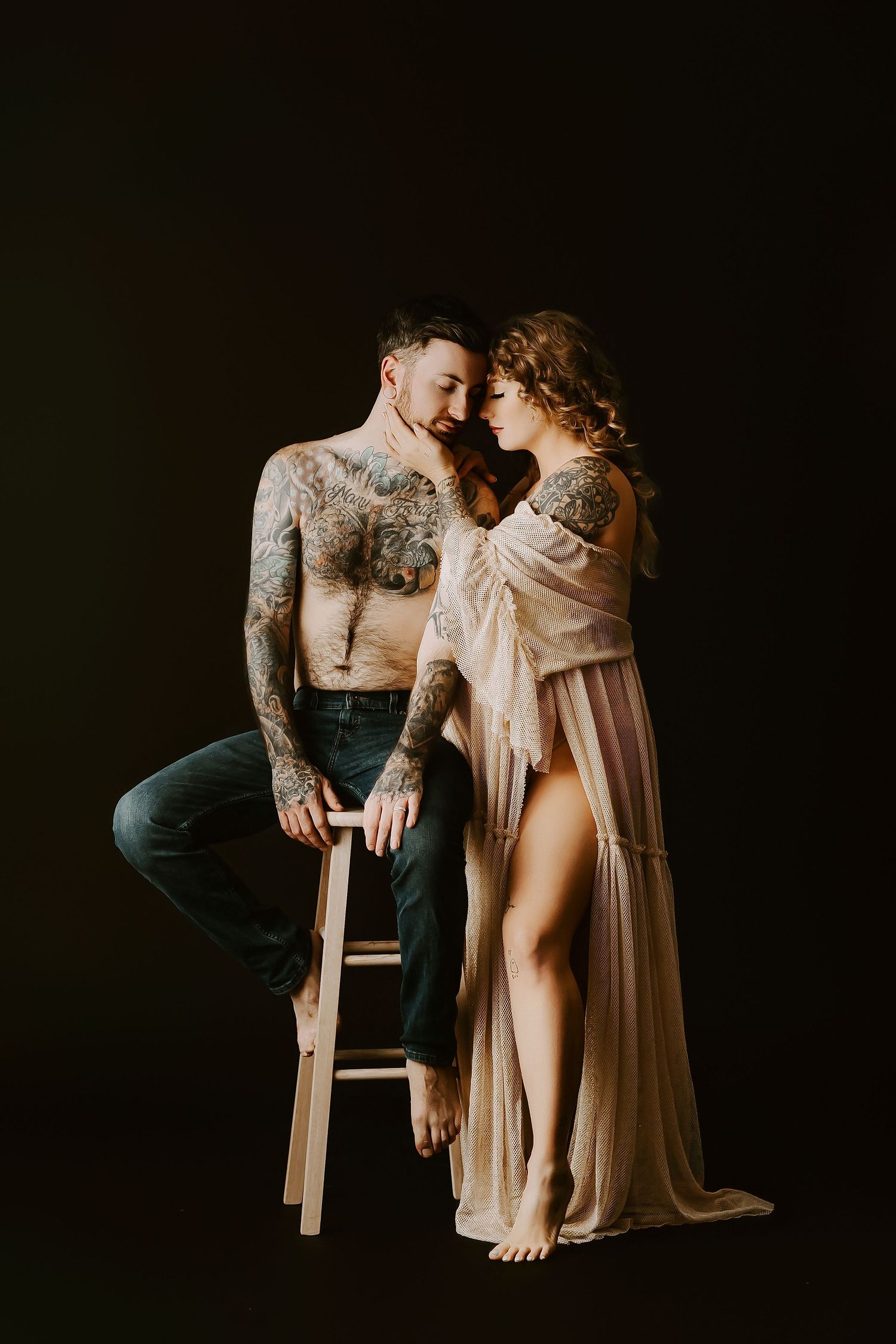 Intimate maternity portrait in dark moody lighting with vintage aesthetic.
