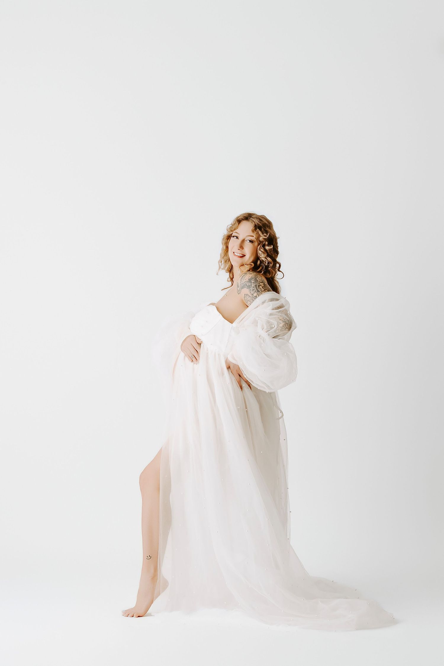 Ethereal studio portraits in white featuring soft, flowing fabric and gentle poses against a bright background.