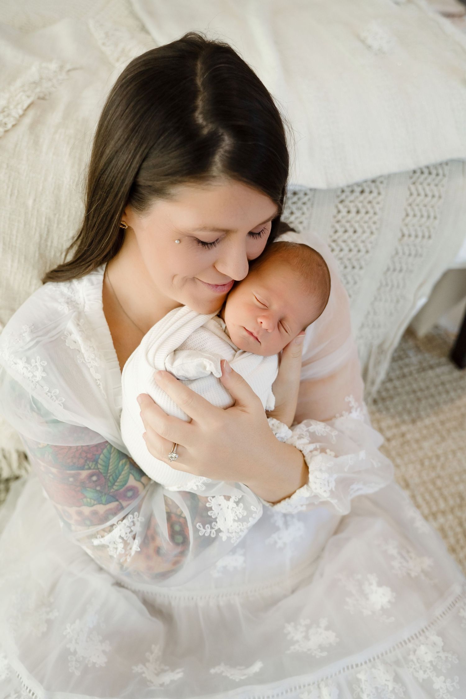 A series of tender moments showing a baby in white lace being gently cradled and kissed.