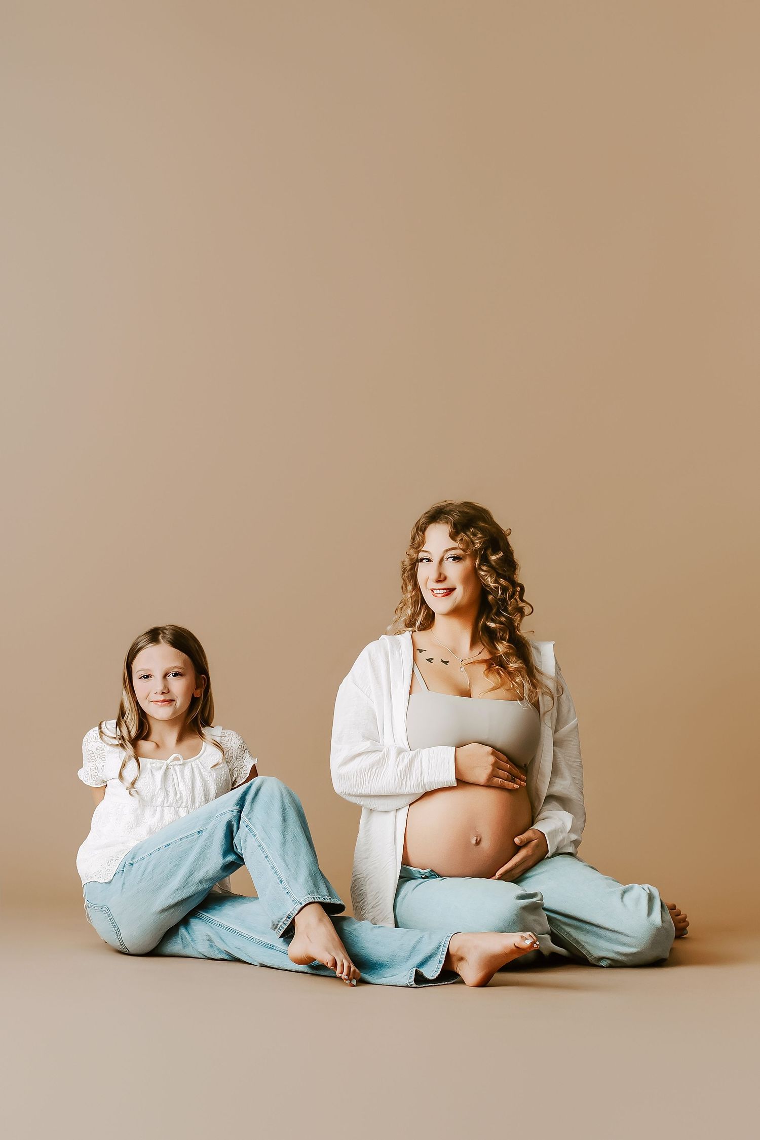 A series of artistic maternity photos showing a woman in a white shirt and blue pants posing against a neutral backdrop.