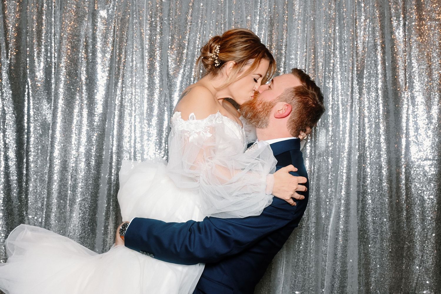 Romantic moment captured against a sparkly silver sequin backdrop.