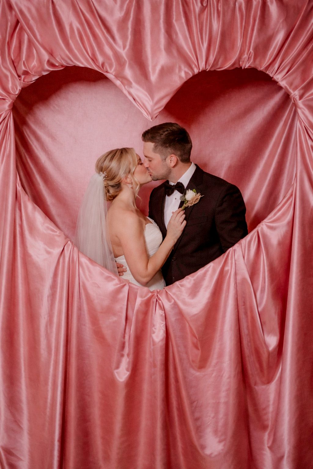 A romantic sequence of four wedding photos showing a couple kissing against a pink satin backdrop.
