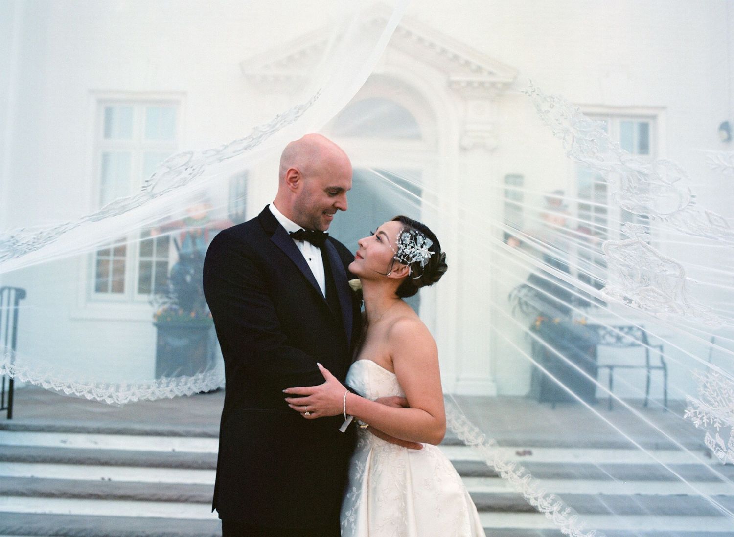Wedding couple embracing on a bright white balcony or terrace.