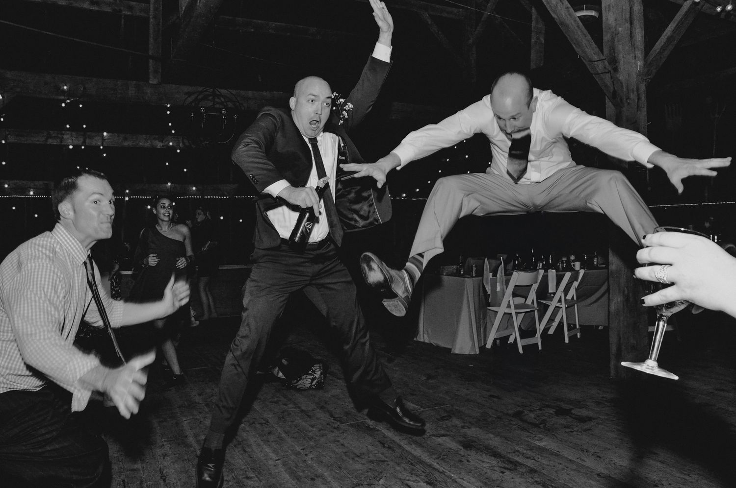 Energetic dance moves captured in black and white at a lively wedding reception.