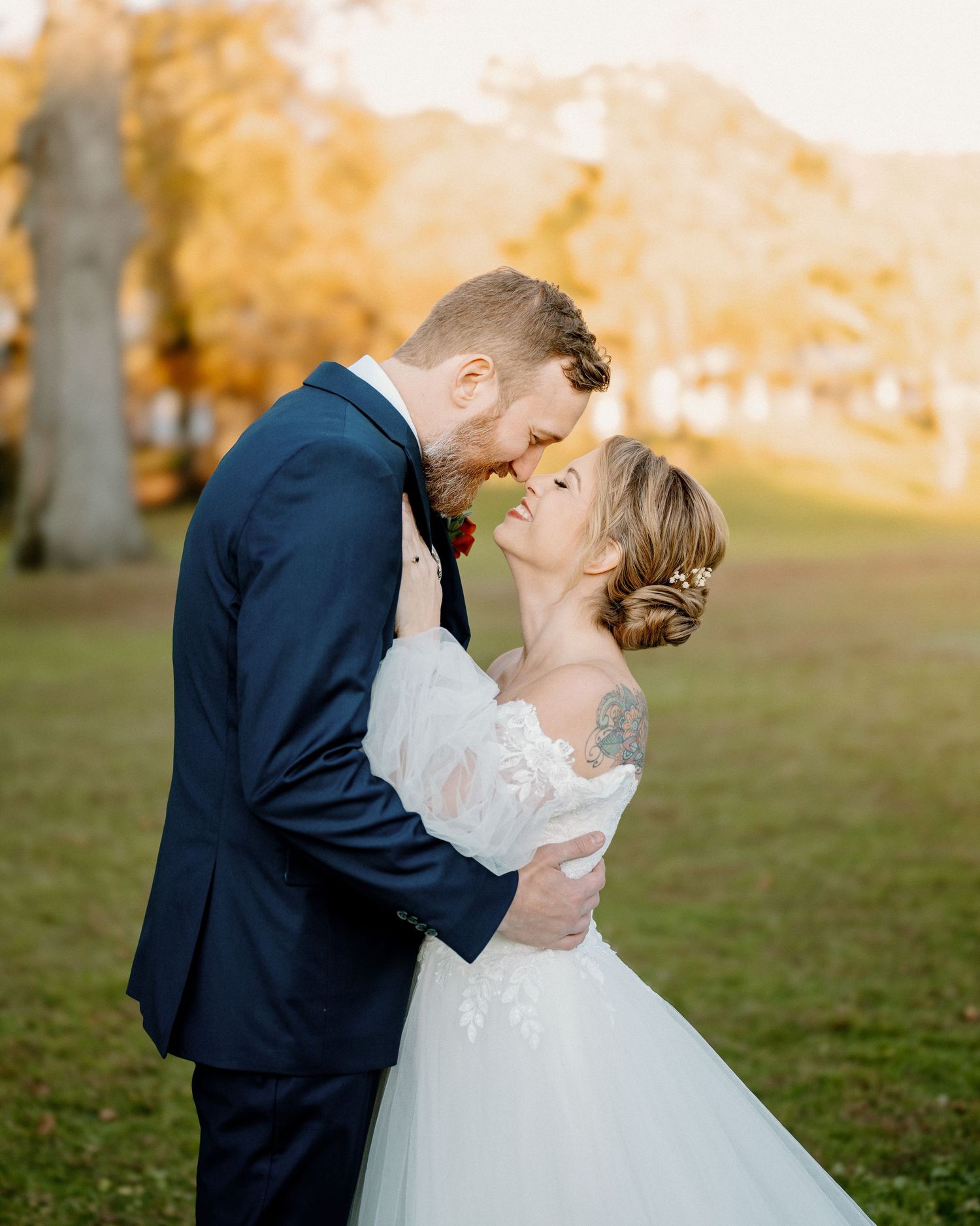 Newlyweds share an intimate moment during golden hour in an outdoor setting.