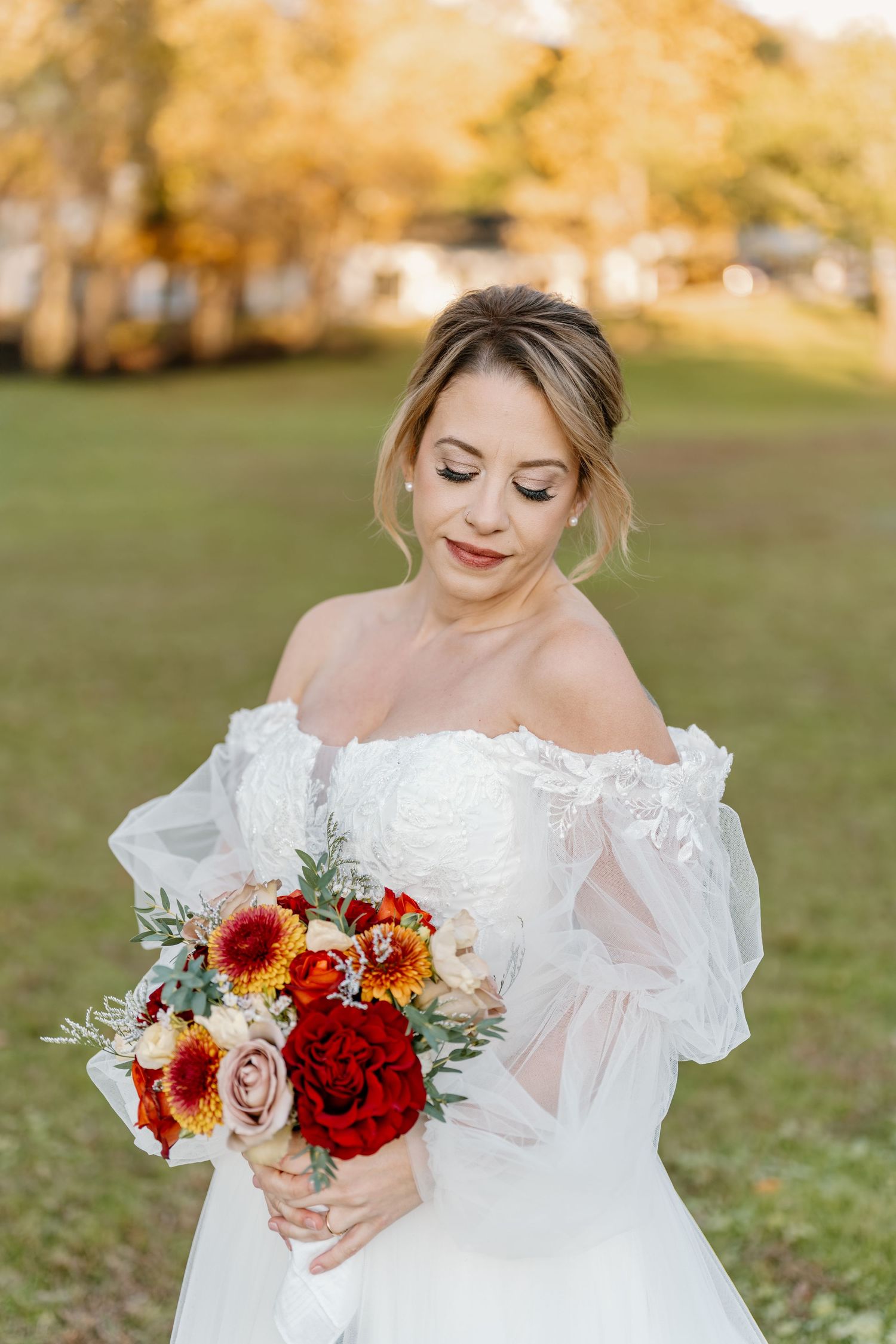 A bridal portrait series showing a white lace wedding dress and vibrant red and orange autumn bouquet in an outdoor setting.