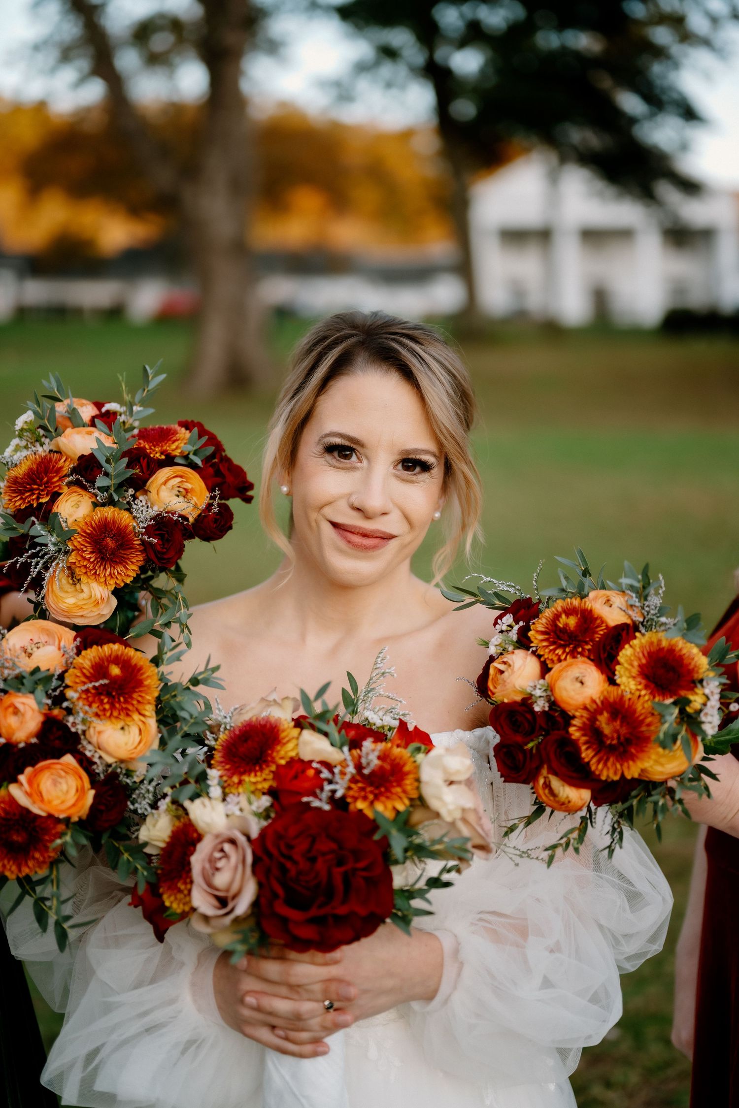 Vibrant autumn wedding bouquet featuring orange, red and burgundy flowers with greenery accents.