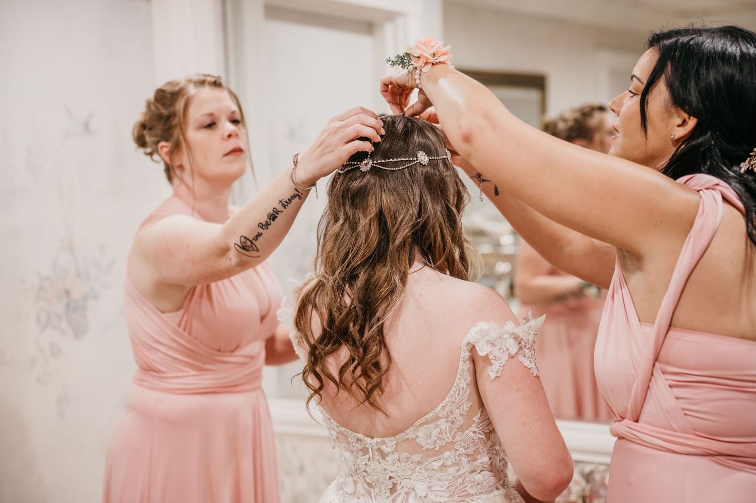 Wedding preparation scene with bridesmaids in pink dresses helping style hair.