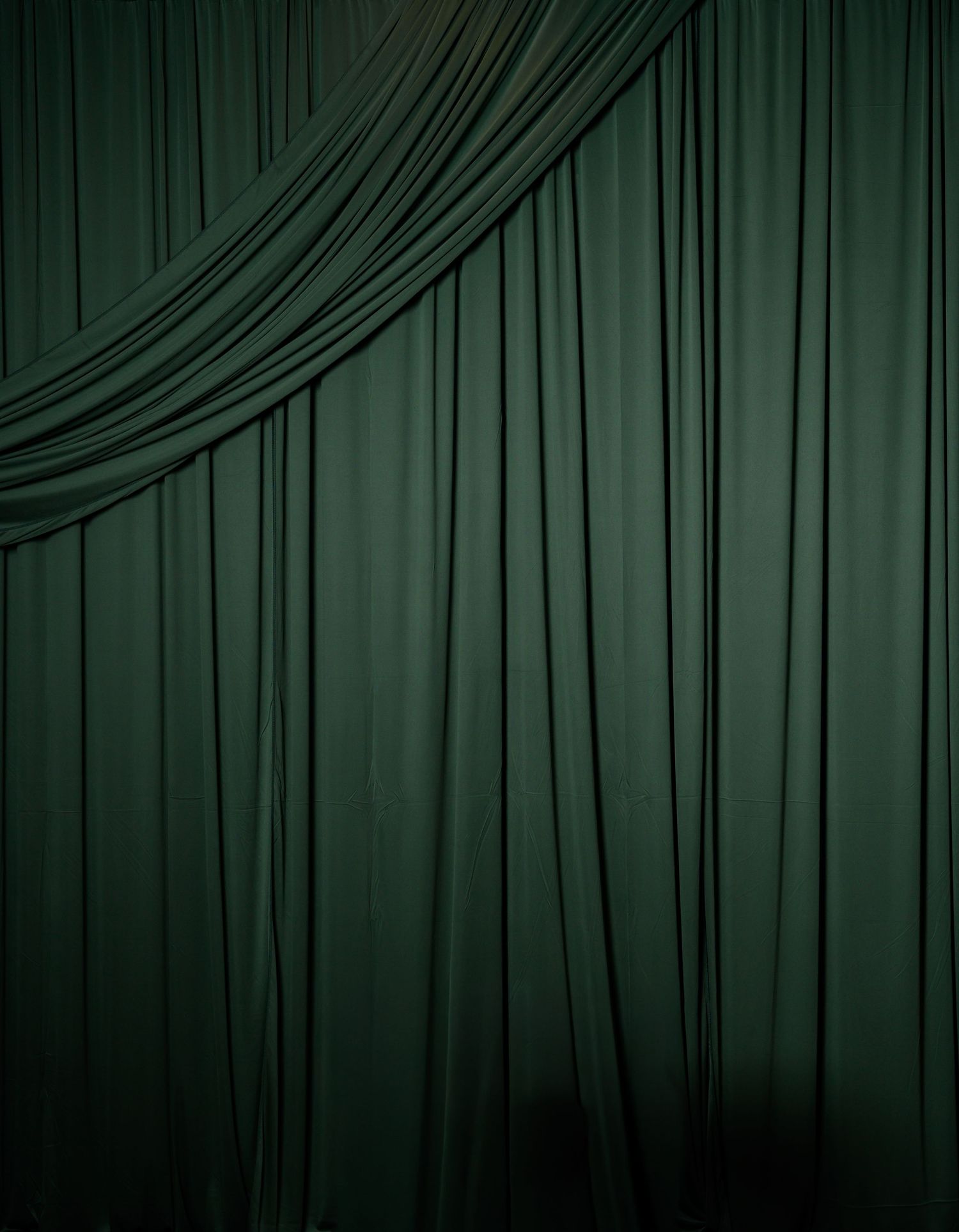 Dramatic dark green velvet curtains with elegant draping and folds.