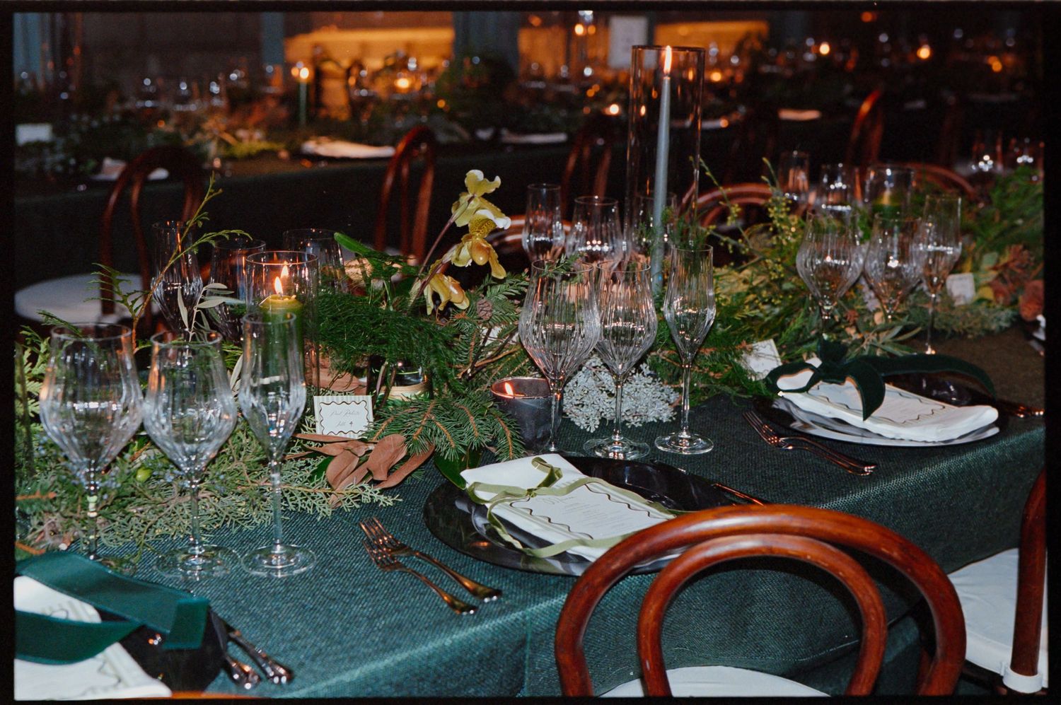 Elegant table setting with wine glasses, greenery and ambient lighting for evening reception.
