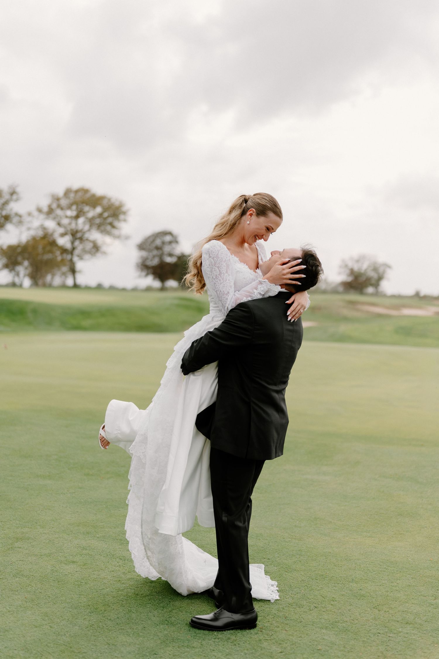 Romantic couple sharing intimate moment on golf course green during wedding photoshoot.