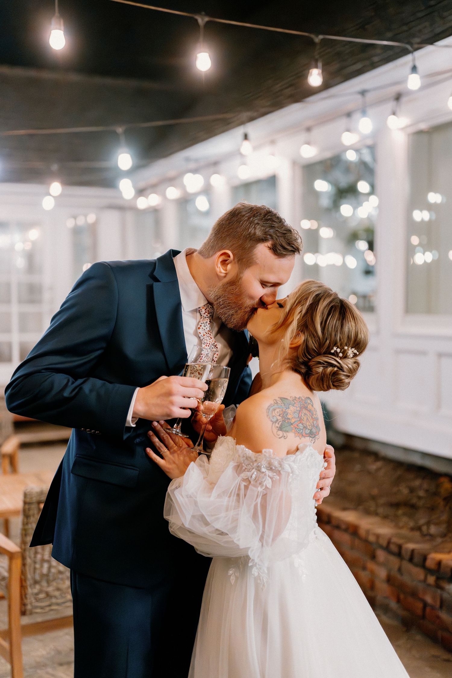 Romantic dance pose in an industrial venue with string lights creating ambient atmosphere.