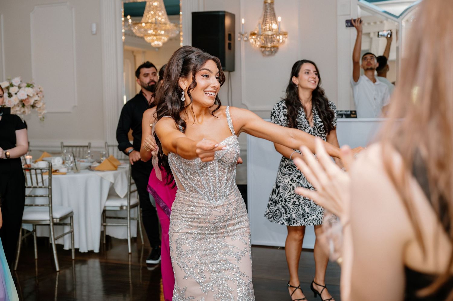 Wedding reception dance floor with guests in sparkly dresses celebrating.
