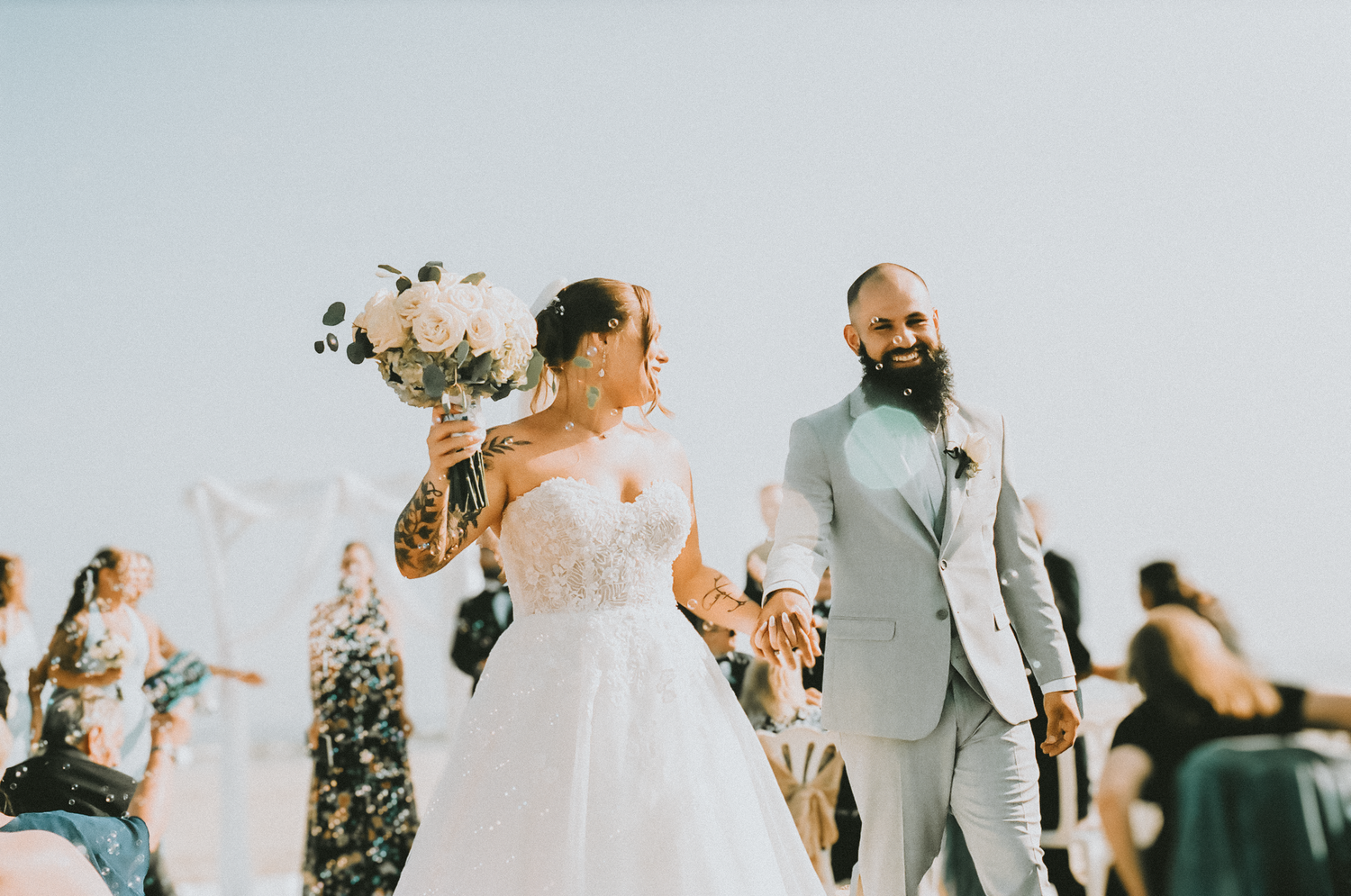 A wedding couple and guests celebrate with confetti during an outdoor ceremony.