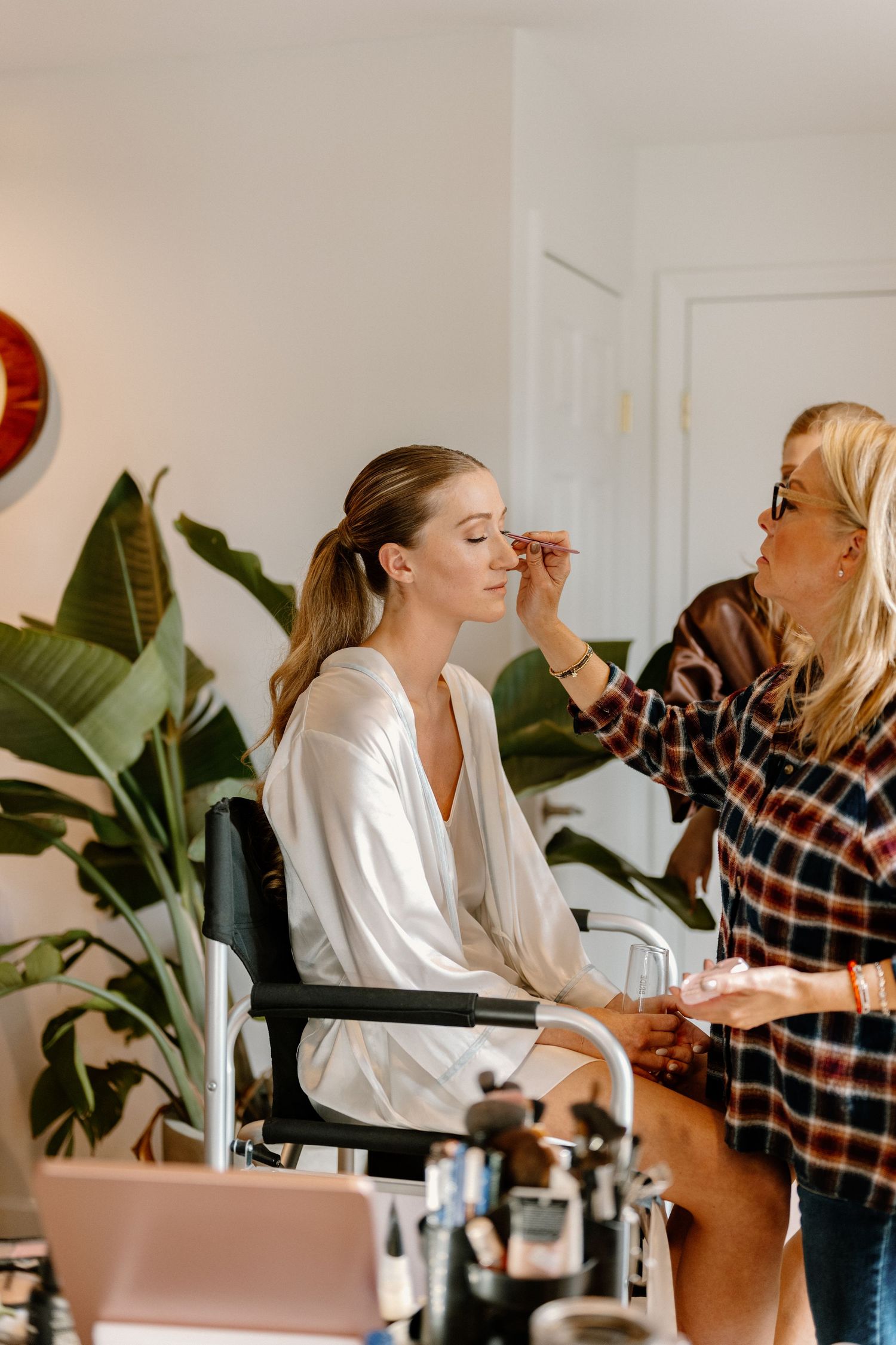 Wedding day preparation scene in a bright room with makeup application.