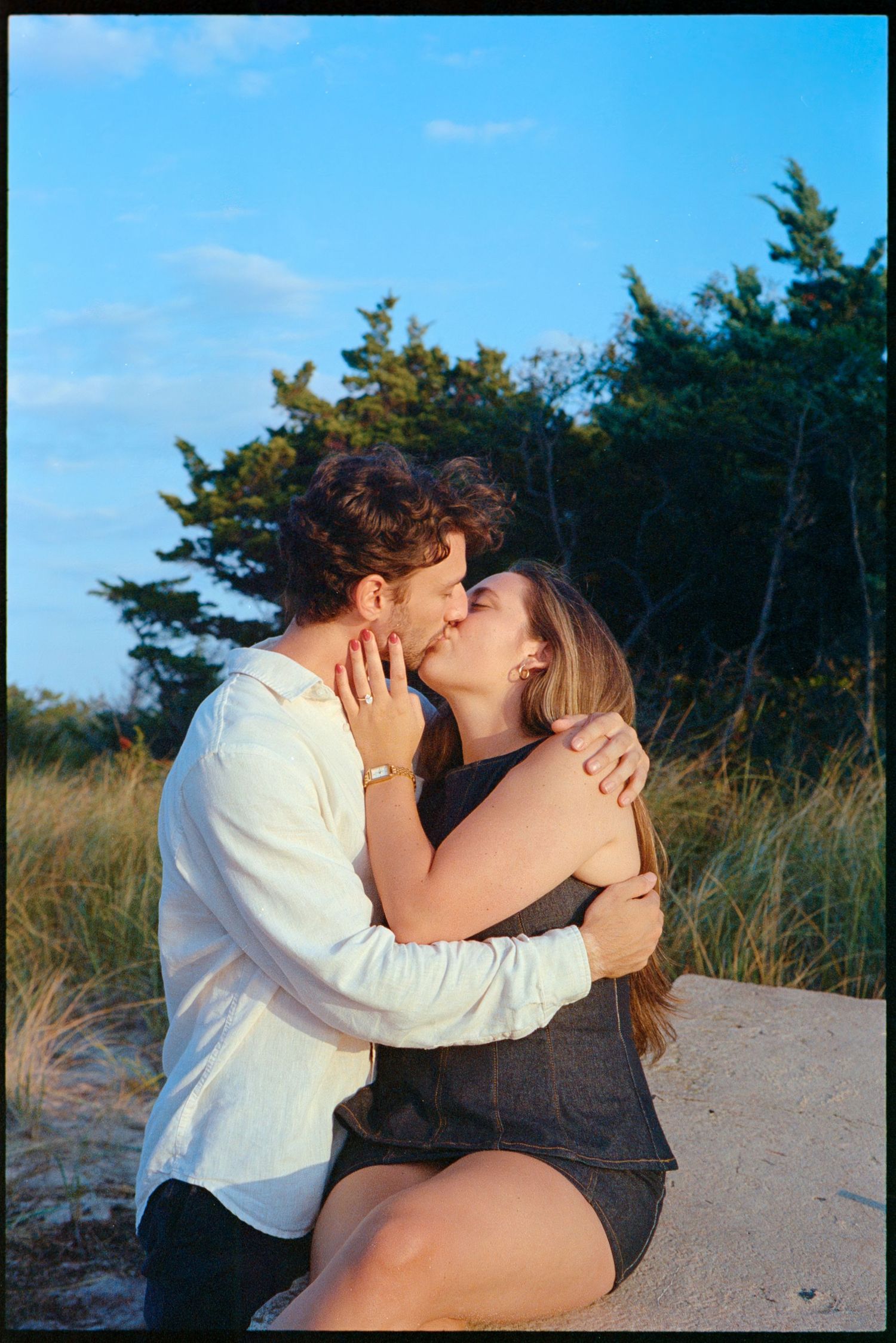 Romantic beach scene with couple sharing intimate moment at sunset.