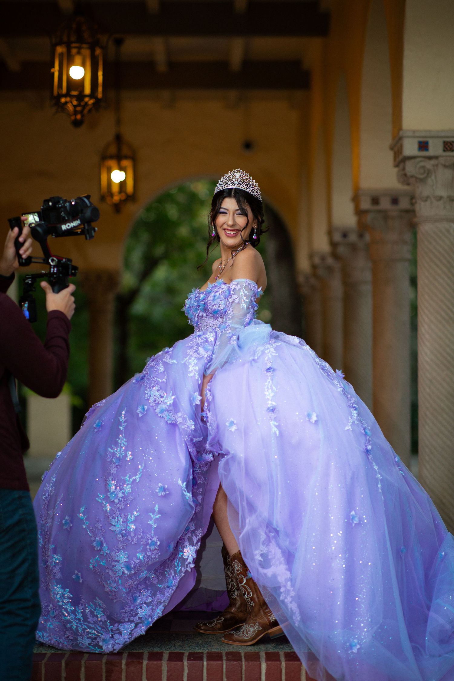 A flowing purple ballgown dress photographed against architectural columns and lanterns.