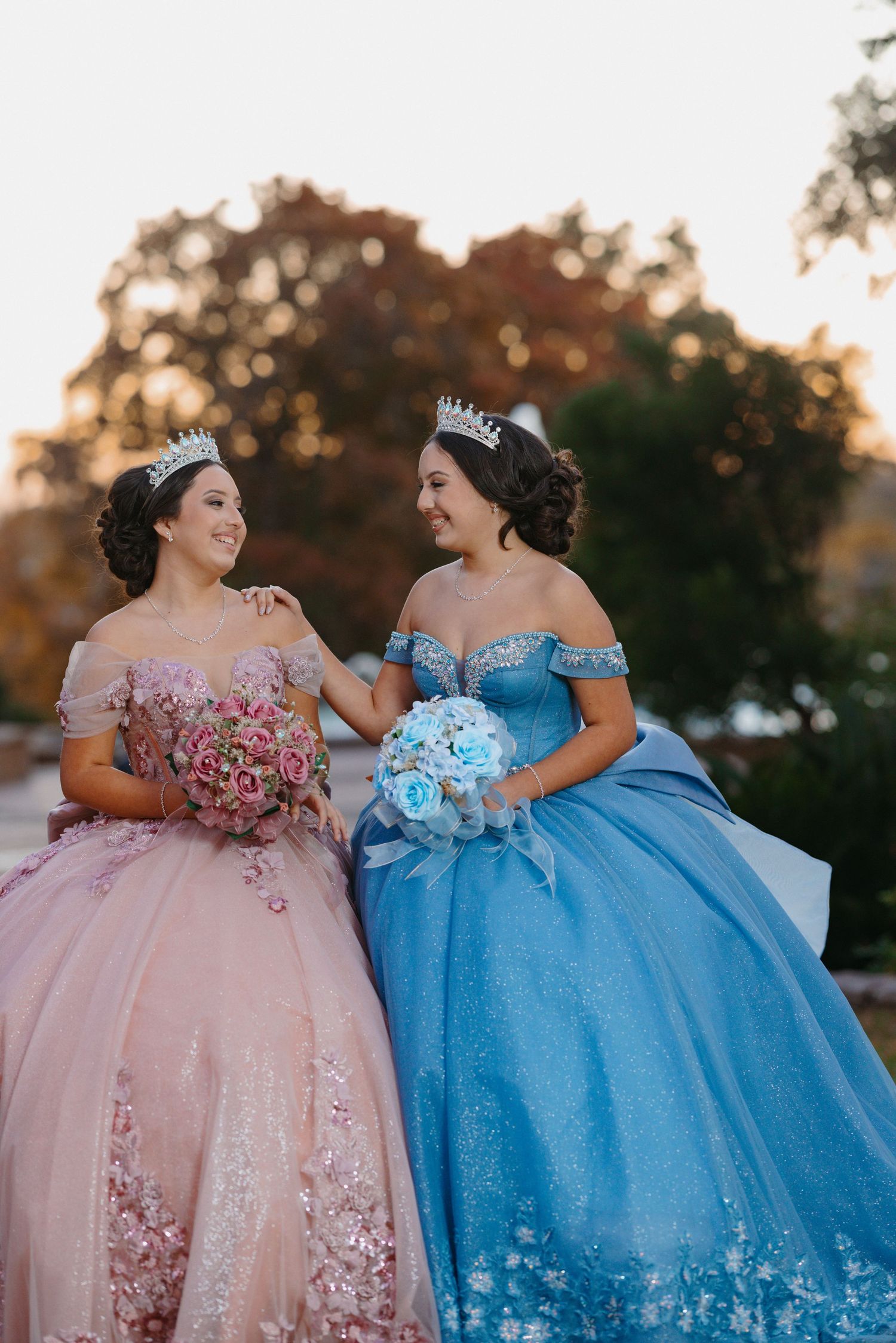 Two stunning ball gowns in pink and blue photographed together during sunset.