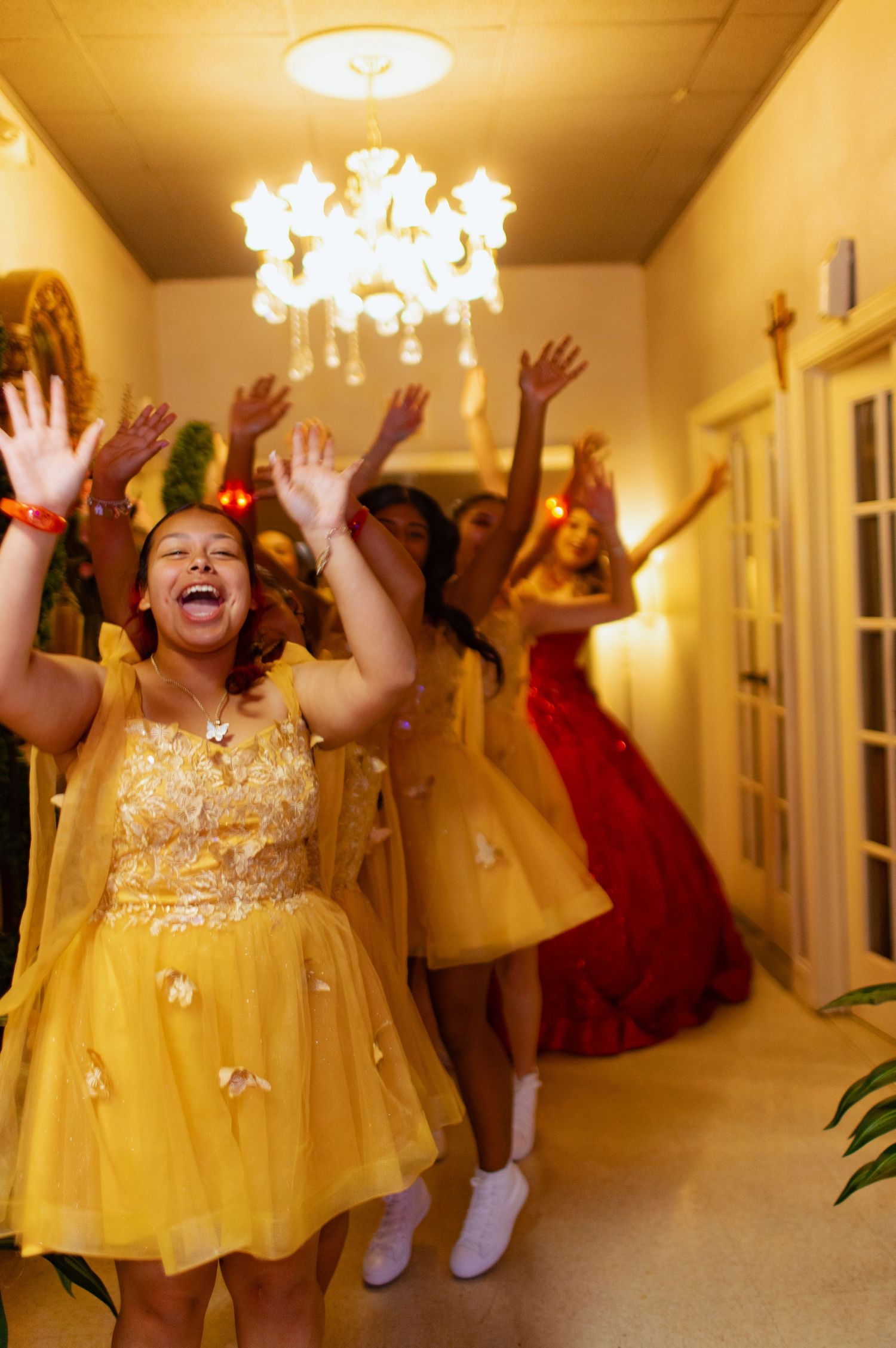 Joyful celebration in yellow dresses under an elegant chandelier.