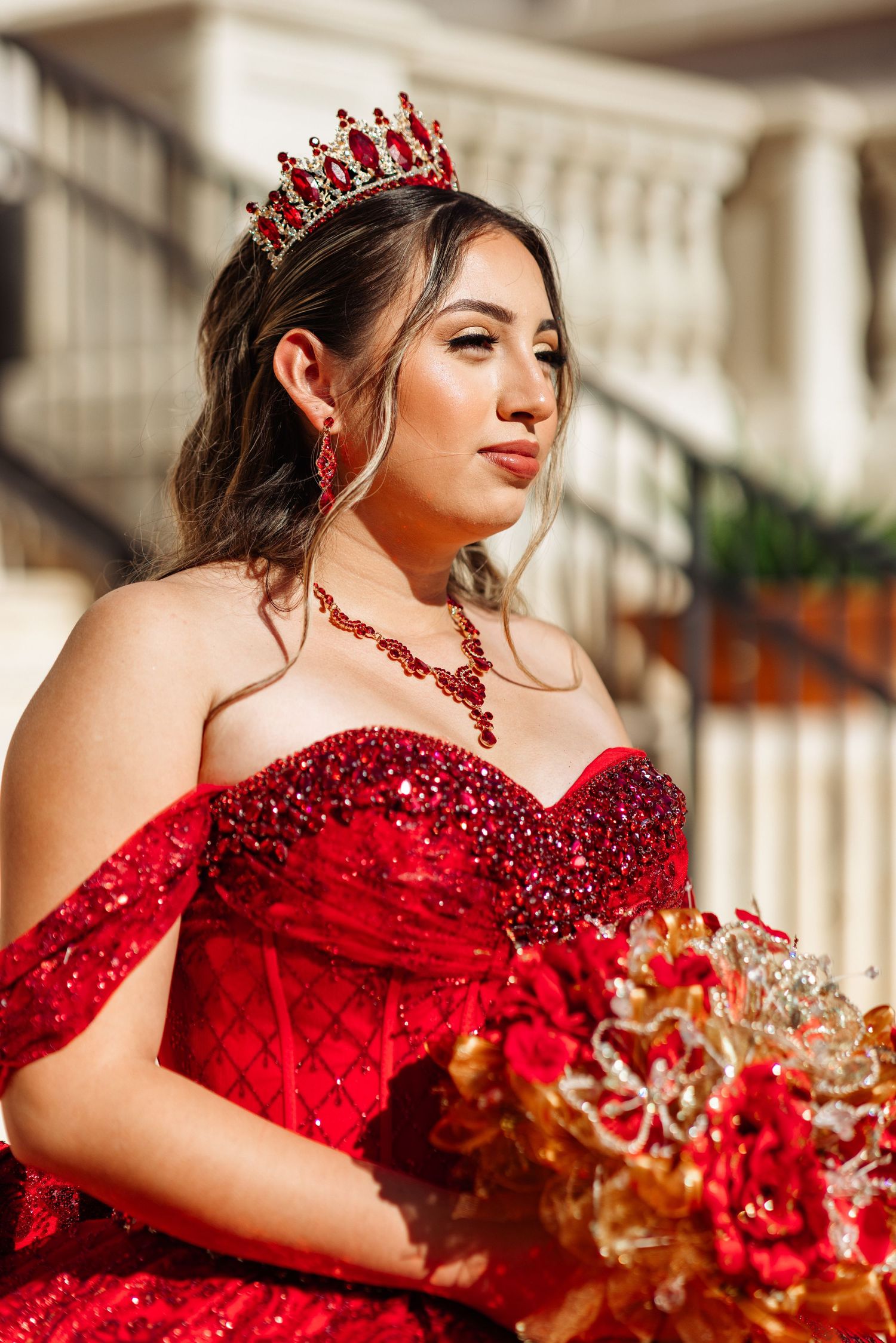 A close-up of a sparkling red ball gown with matching crown and jewelry.
