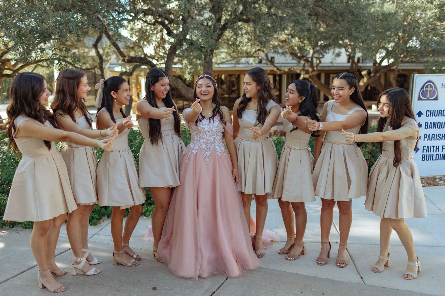 Bridesmaids in matching cream and pink dresses pose together outdoors.