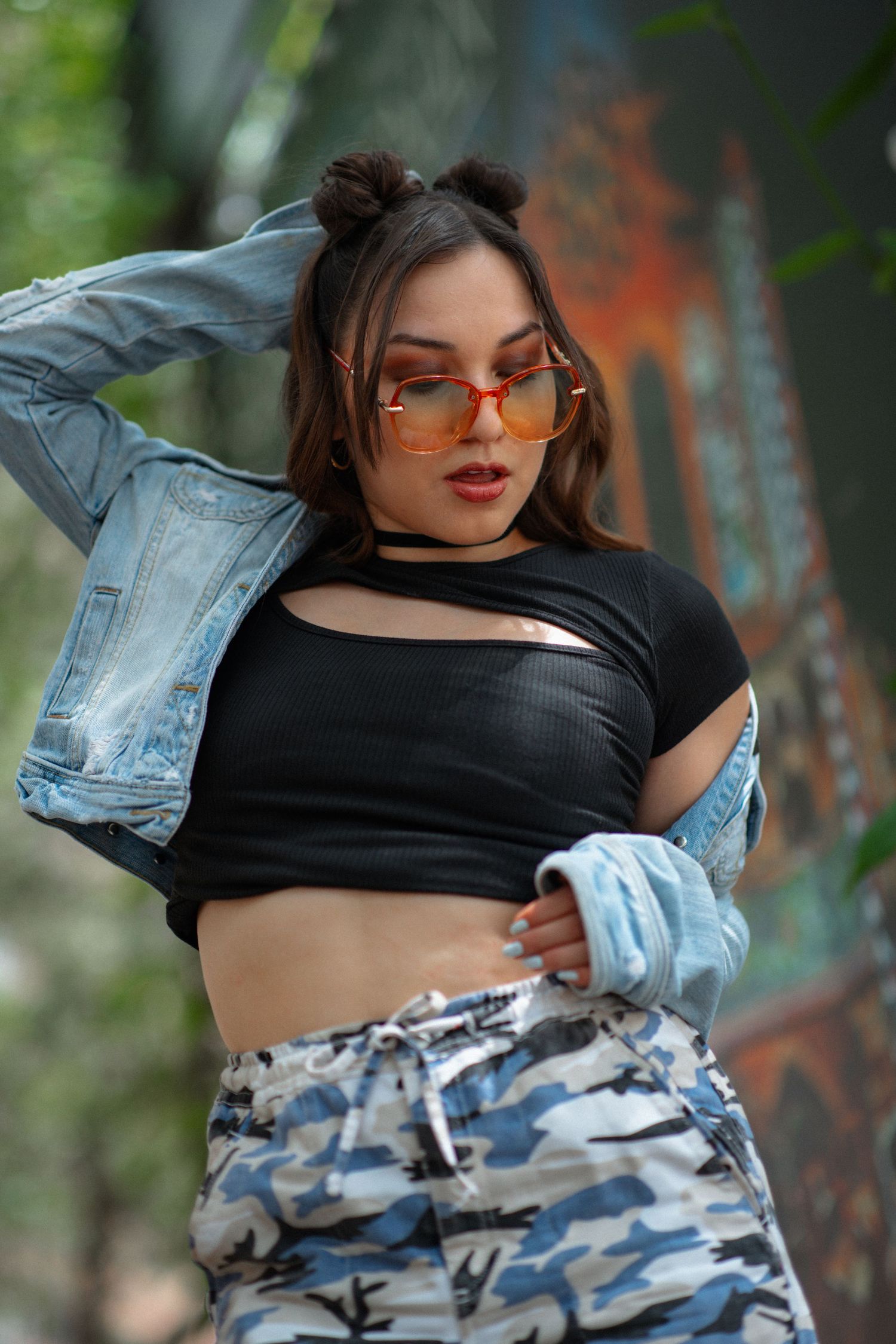 Urban fashion shoot featuring denim jacket and camo pants in industrial setting.