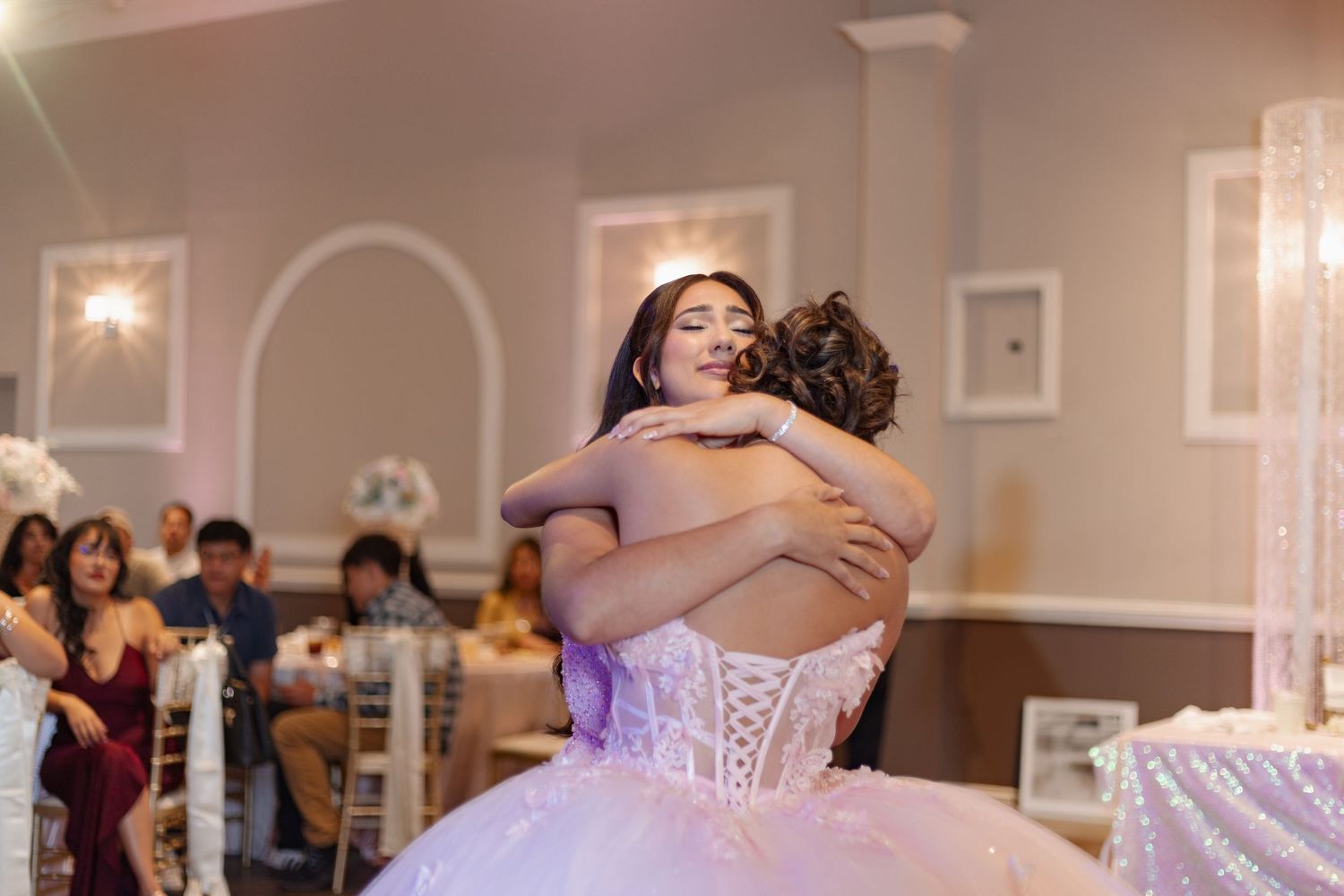 Wedding reception venue decorated in white and pink with elegant lighting and floral arrangements.