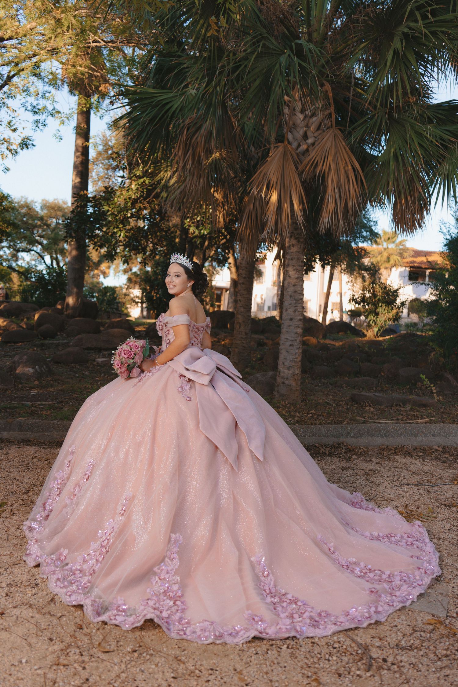 Blush pink princess ball gown with delicate floral details spread across a natural outdoor setting.