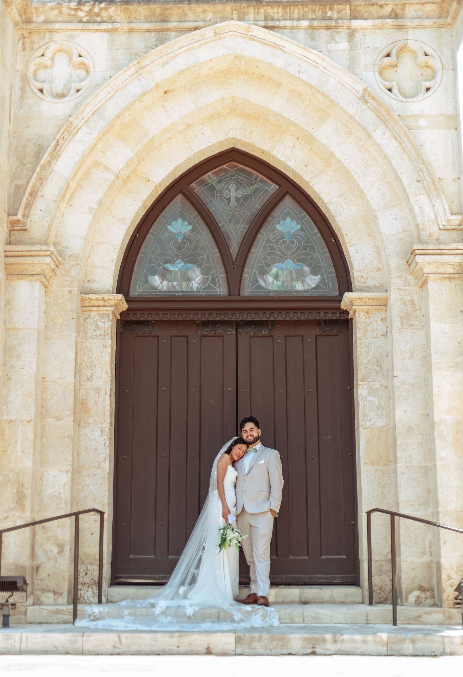 Wedding couple portraits against historic stone church with beautiful arched doorways.