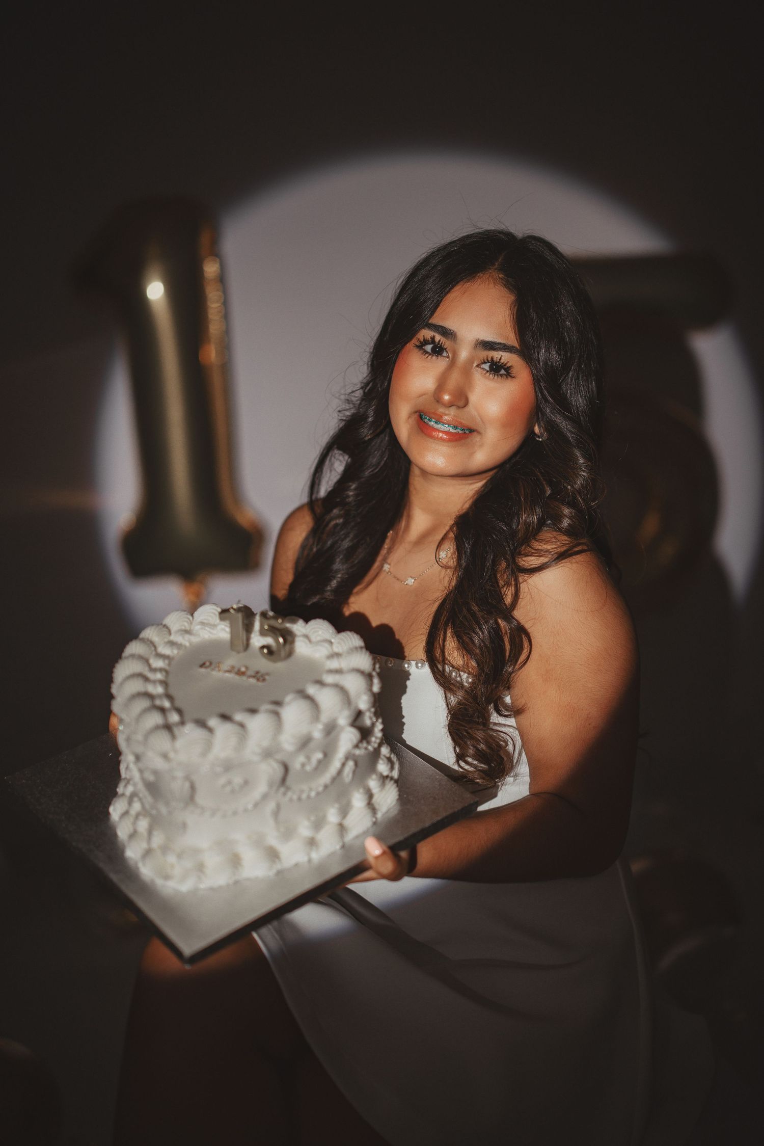 Celebration photo featuring white frosted cake and dramatic spotlight lighting.