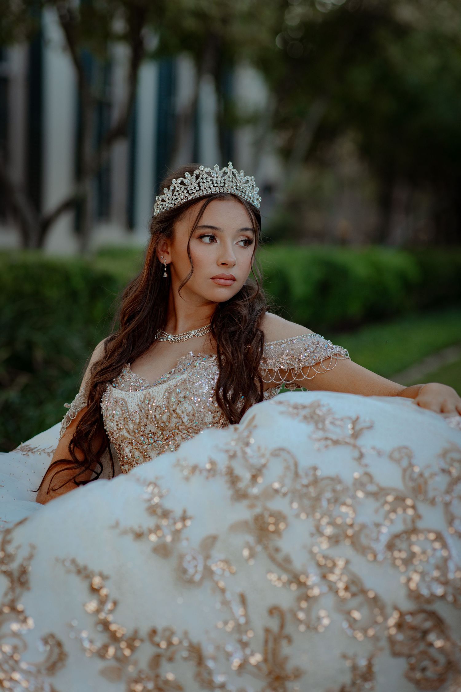 Elegant champagne-colored ballgown with crystal embellishments in an outdoor setting.