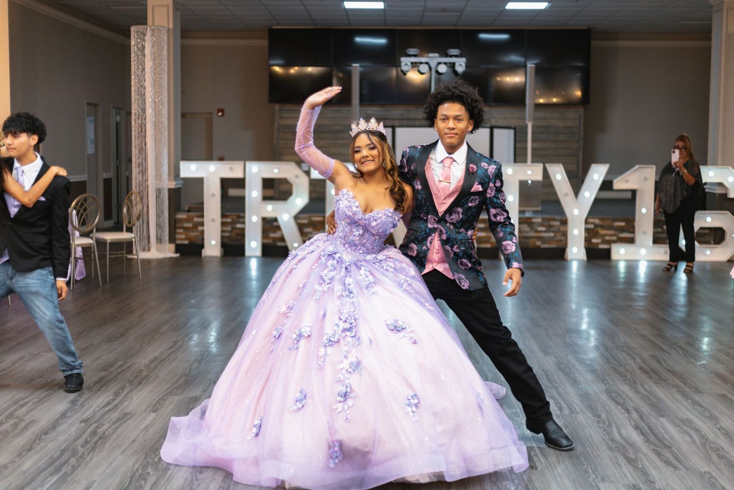 A couple celebrates in a lavish ballroom with a purple ballgown and formal attire.