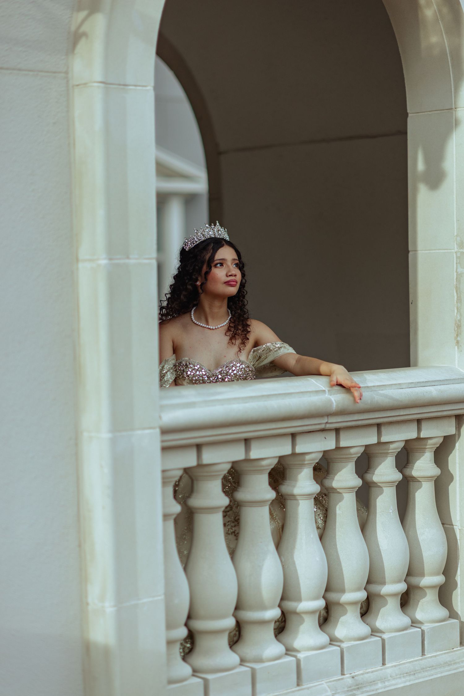 An elegant bridal portrait framed by white stone archways and balustrades.