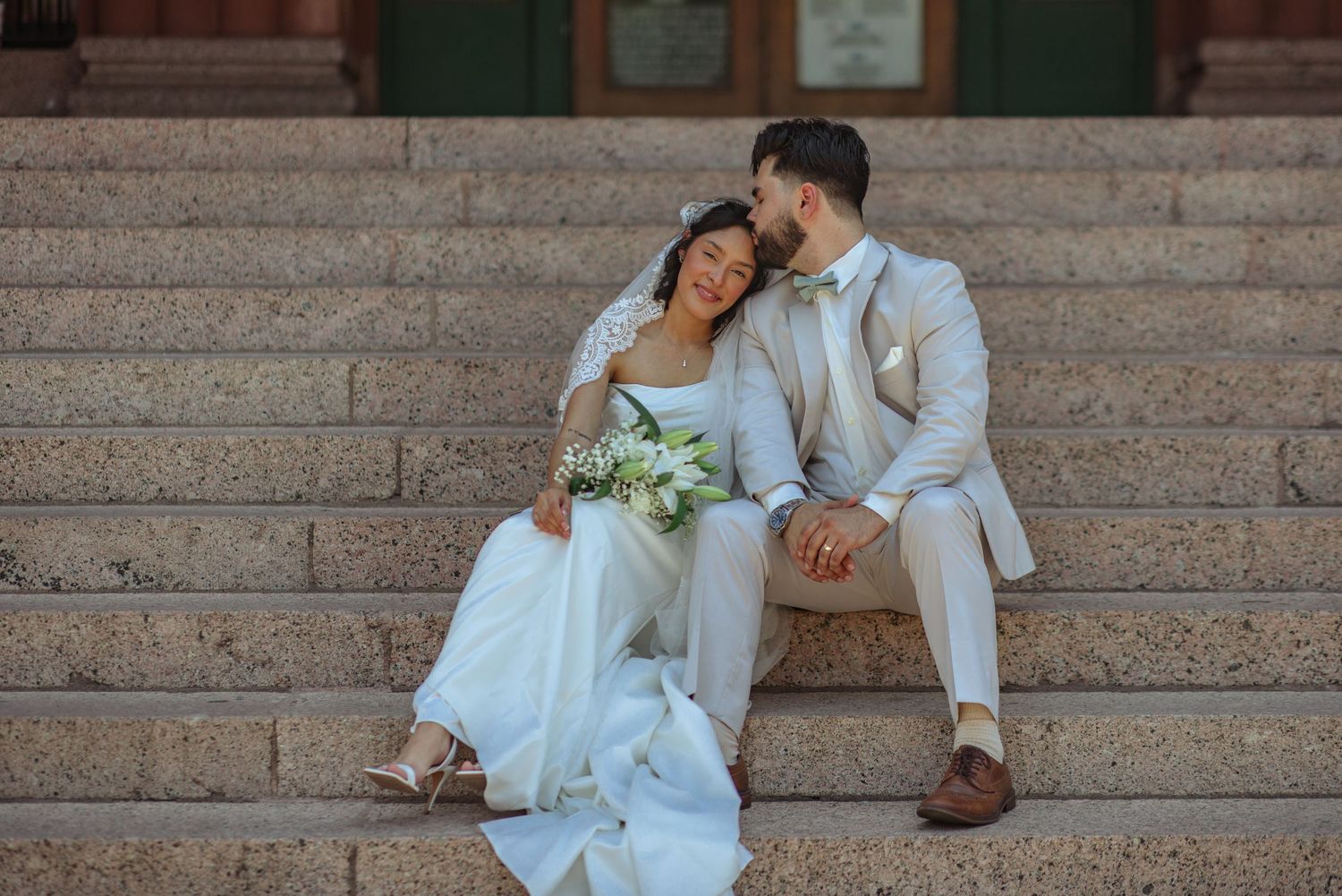 Bride and groom sharing intimate moments on grand stone church steps.