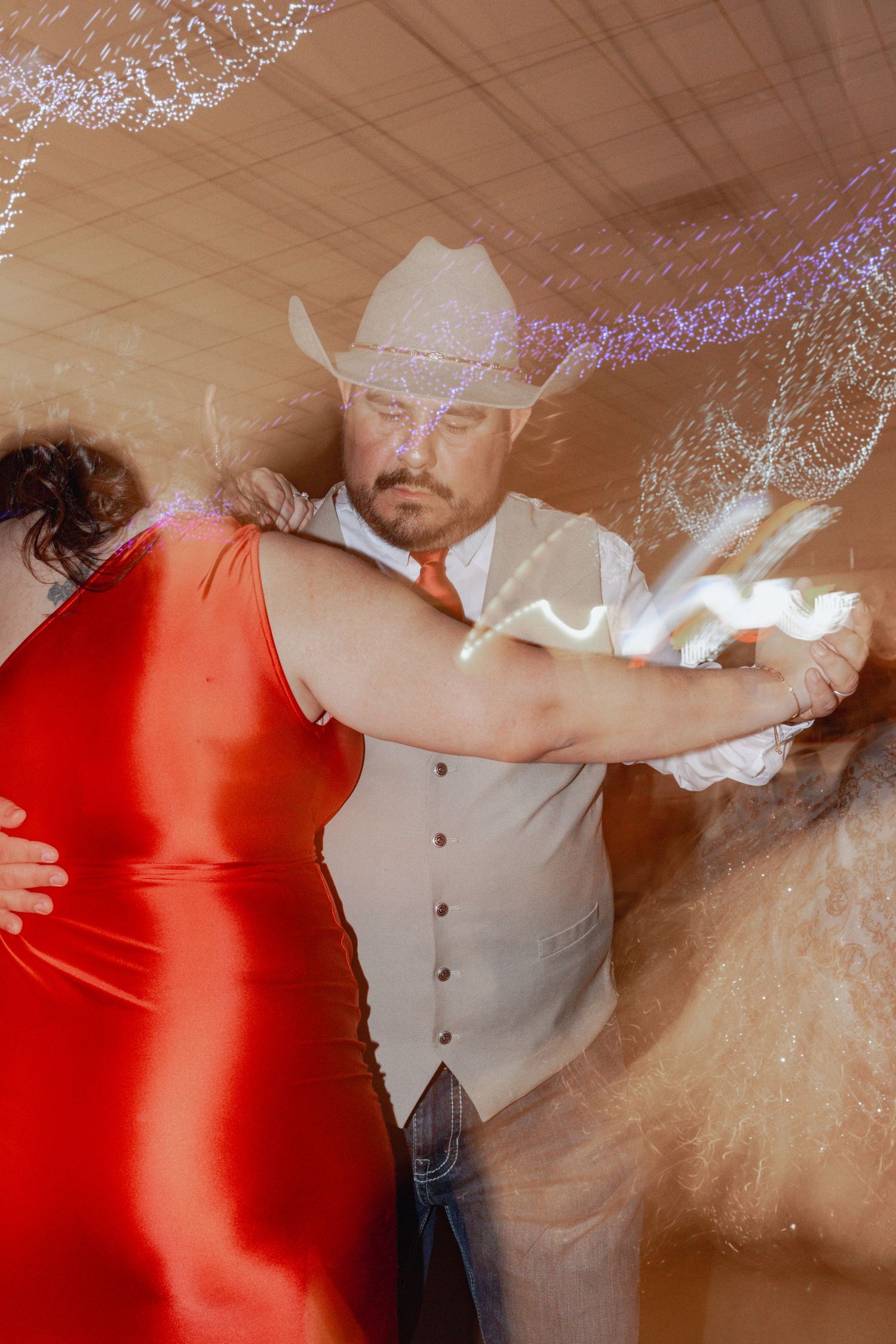People dancing at a celebration, with someone in red and others in formal attire.